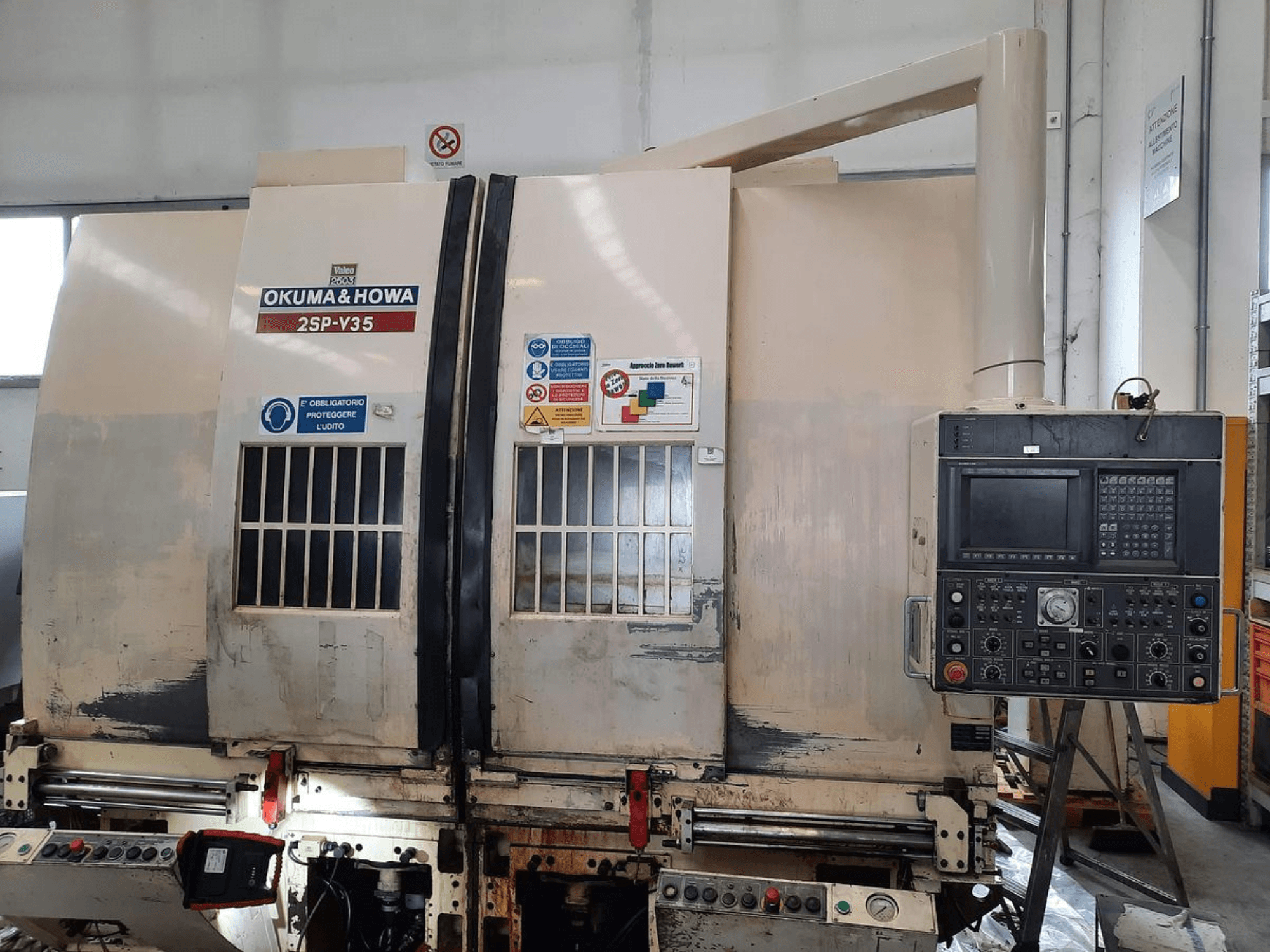 OKUMA & HOWA 2SP-V35 CNC machine viewed from the front, featuring control panel with various buttons and safety labels.