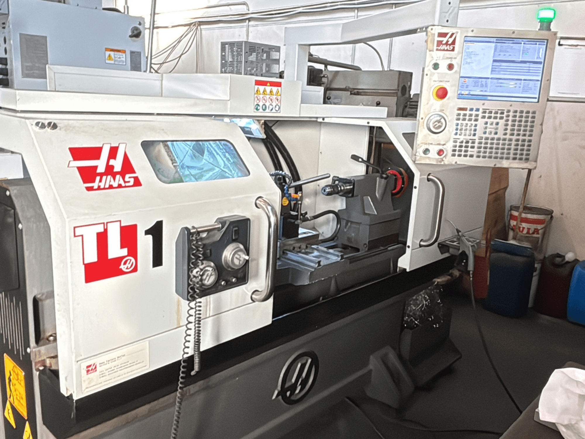 Haas TL-1 CNC lathe machine, front view, features control panel with display, tool holder, and safety labels.