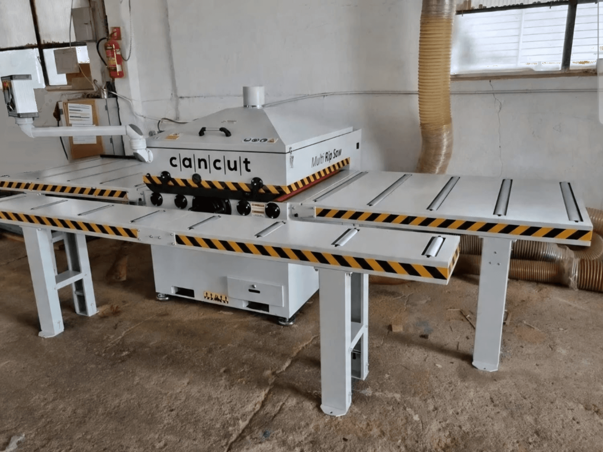 Circular wood saw CAN CUT MC 930 with dual safety-striped tables, viewed from the front in an indoor workshop setting.