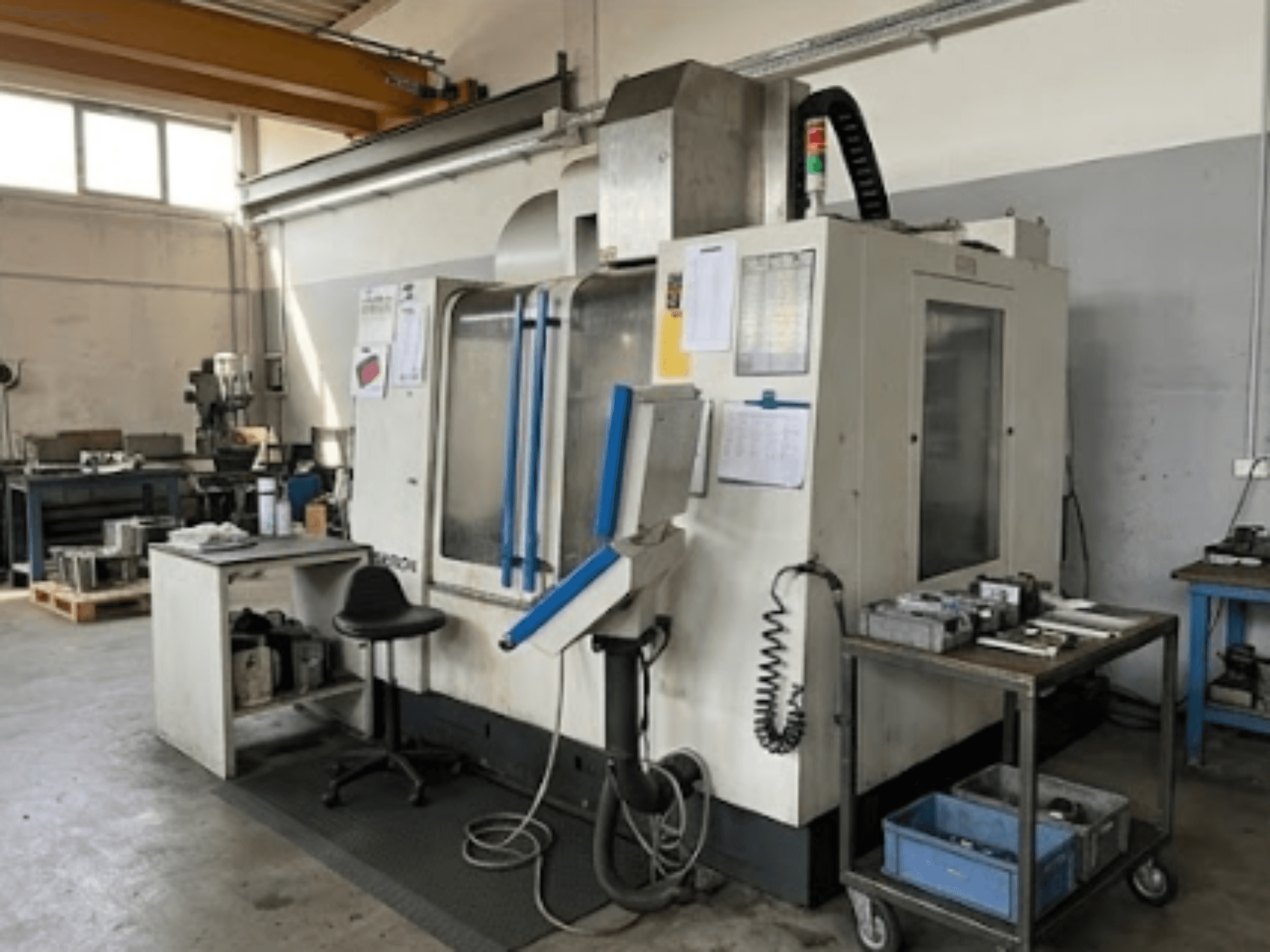 MIKRON VCE 1000 Pro vertical machining center in a workshop, front view with blue accents and adjacent worktable.