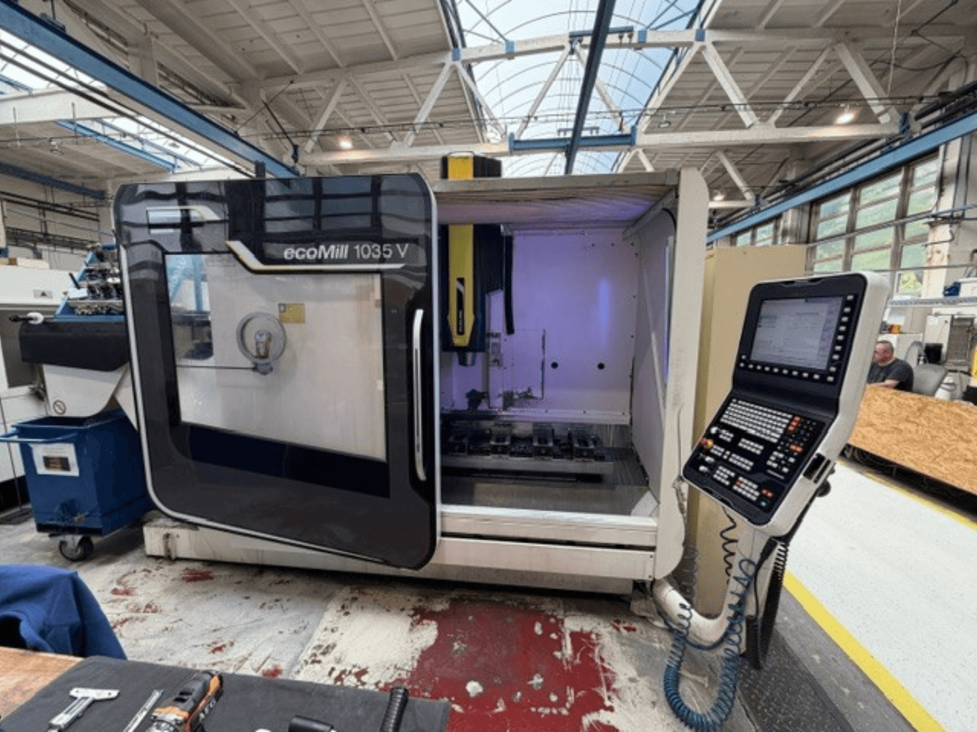 Front view of DMG MORI ecoMill 1035V vertical machining center with open door, showcasing the control panel and work area inside.