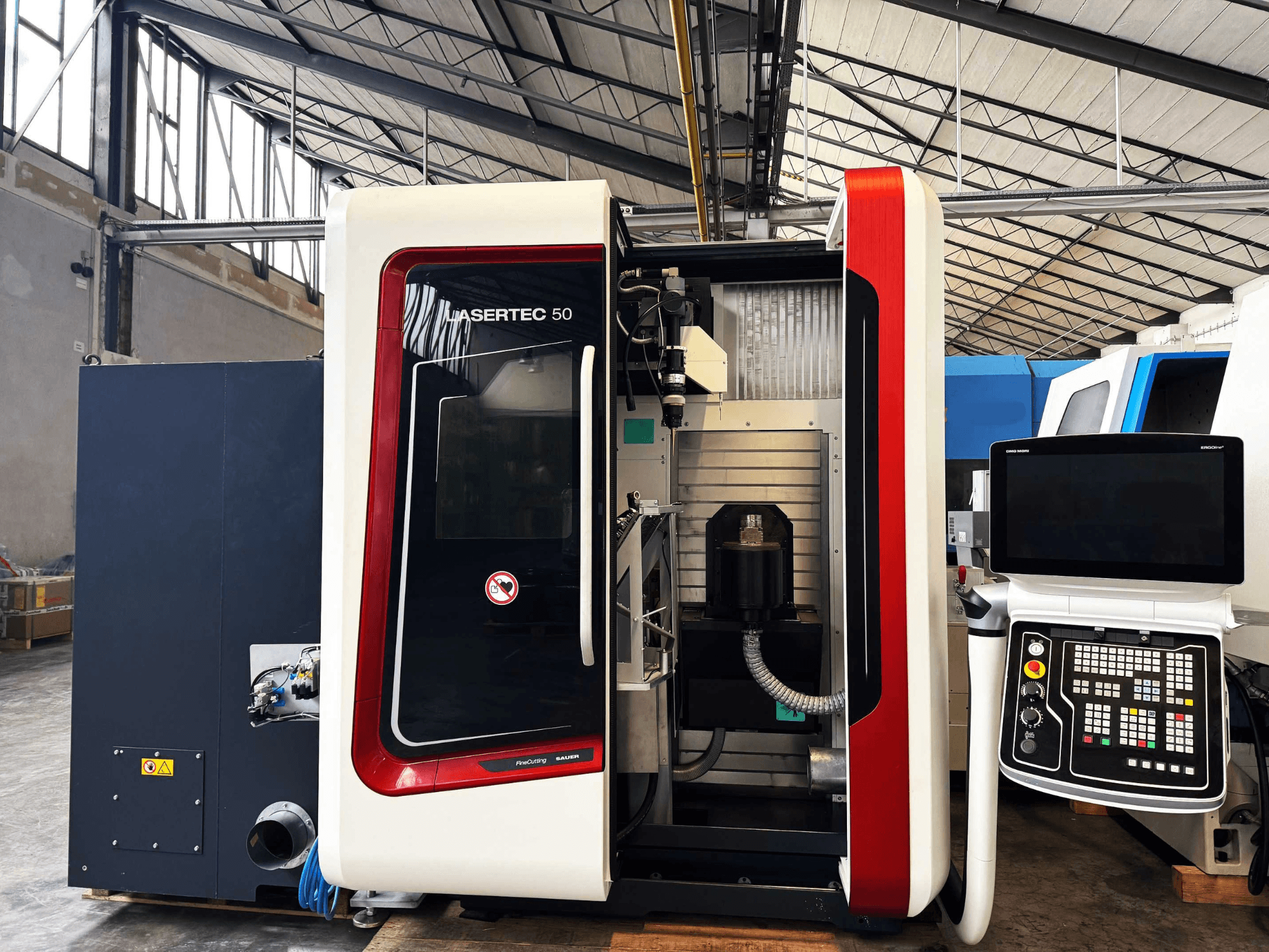 LaserTec 50 CNC machine in a side view, featuring a black and white control panel, visible tool holder, and industrial setting.