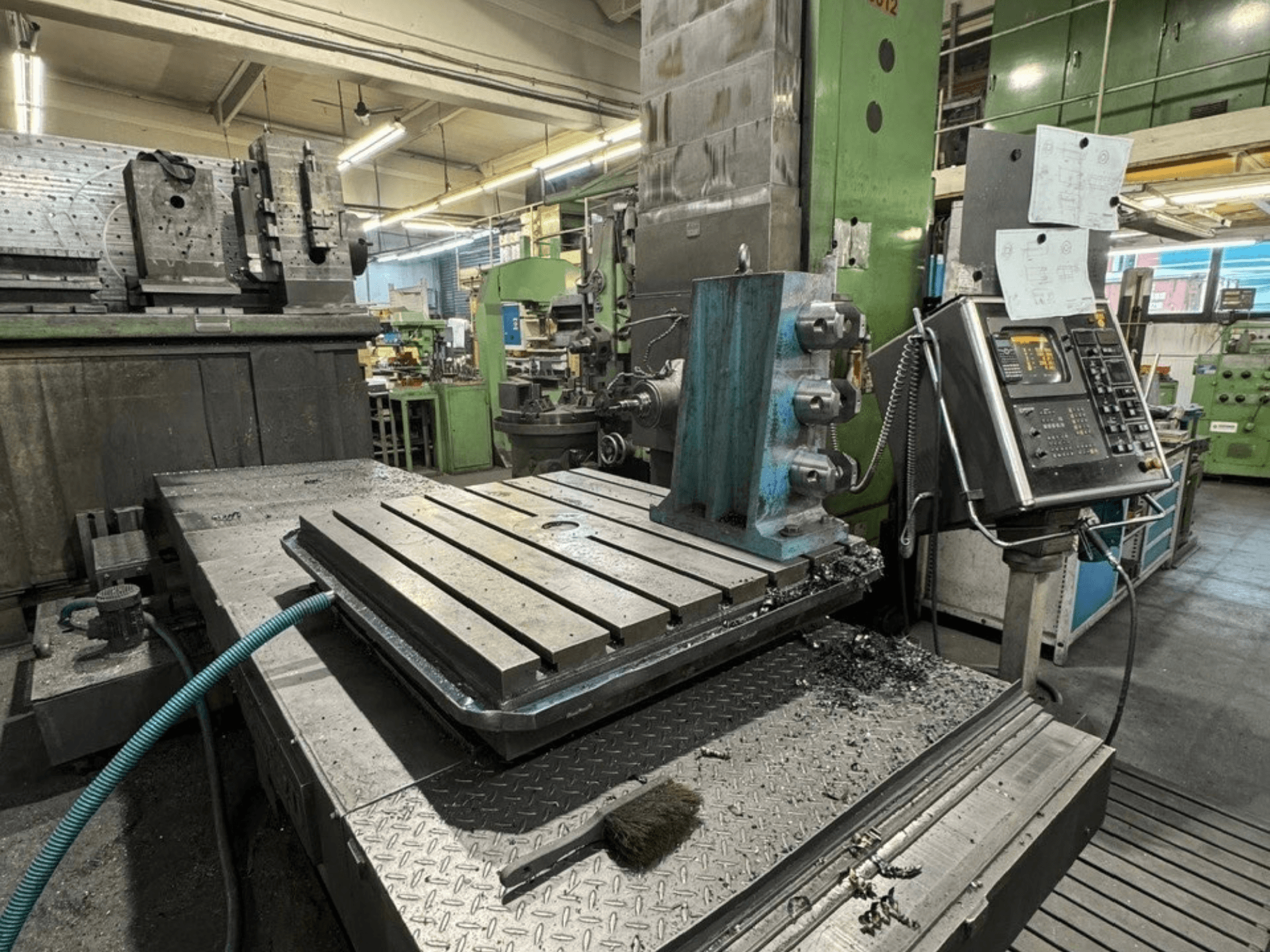JUARISTI 12/TS1.7 boring machine in a workshop, side view showing metal table with grooves and control panel nearby.