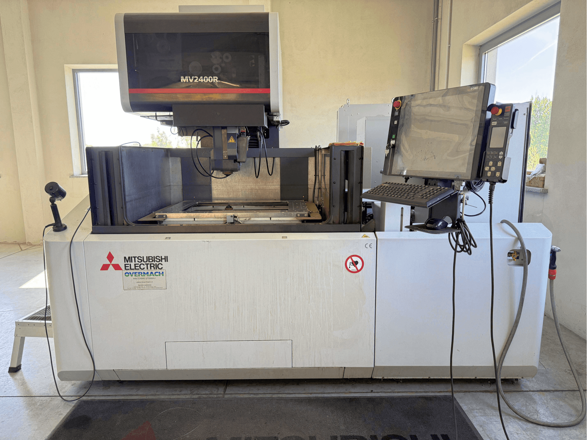 Mitsubishi MV2400R wire EDM machine in front view, featuring a control panel, workspace, and safety signage.