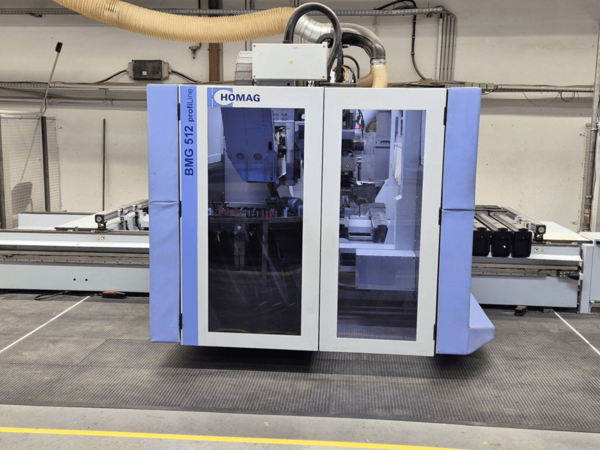 HOMAG BMG 512 ProfiLine CNC machine, front view, featuring a glass panel, precision tools visible, and industrial setting.