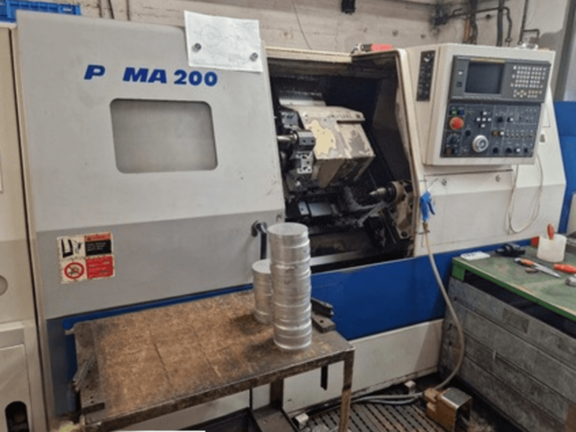 DAEWOO EcoTurn 200 horizontal turning machine, front view, with aluminum workpieces on a table, control panel visible.