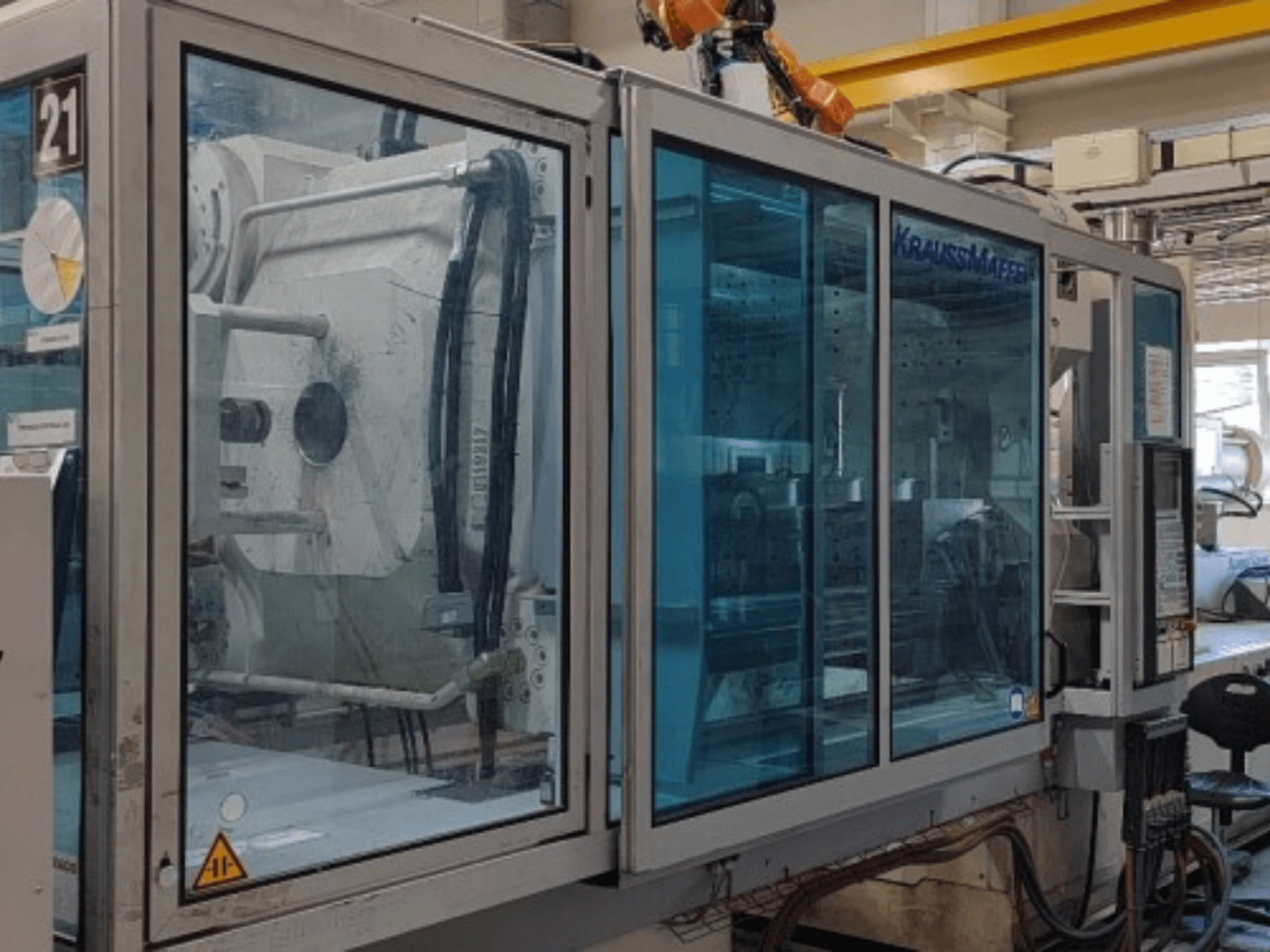 Krauss Maffei KM 575-2700 C2 hydraulic injection moulding machine, side view, featuring transparent safety panels and control panel.