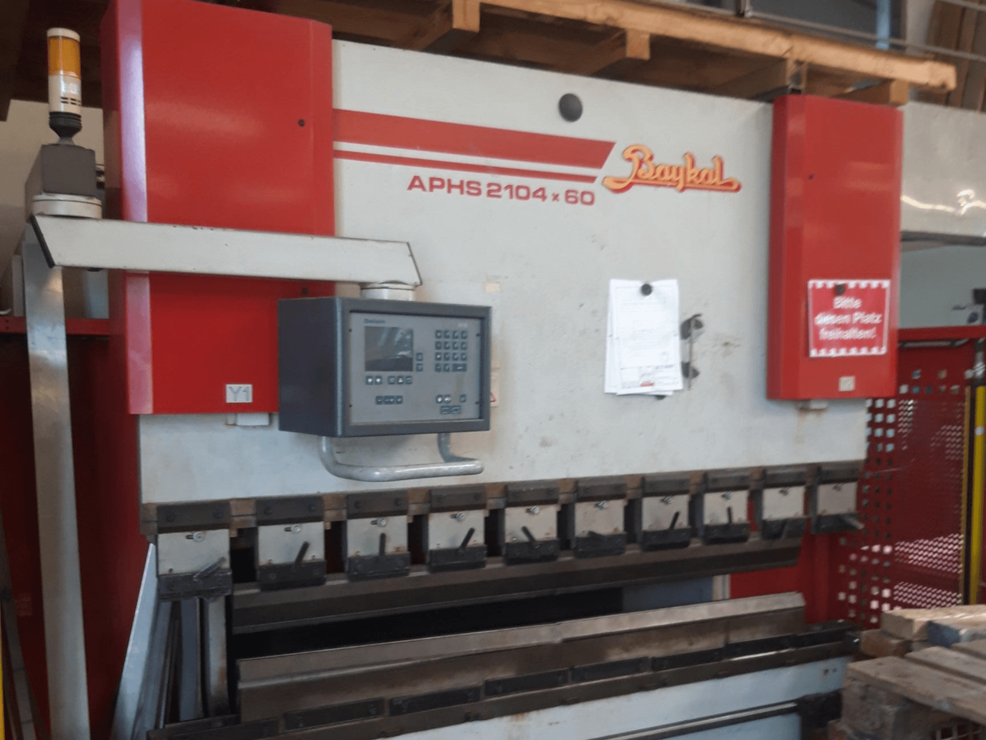 Baykal APHS 2104x60 press brake in front view, featuring control panel and bending tools, set in a workshop environment.