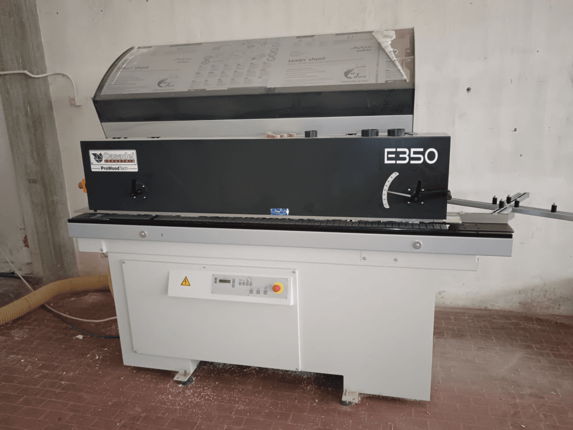 Cesaroli ProWoodtech E350, side view of a woodworking machine with control panel and dust accumulation, mounted on a white base.