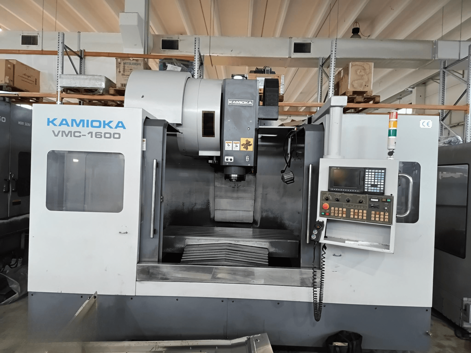 Kamioka VMC-1600 vertical machining center in a factory setting, front view with control panel and visible machining bed.