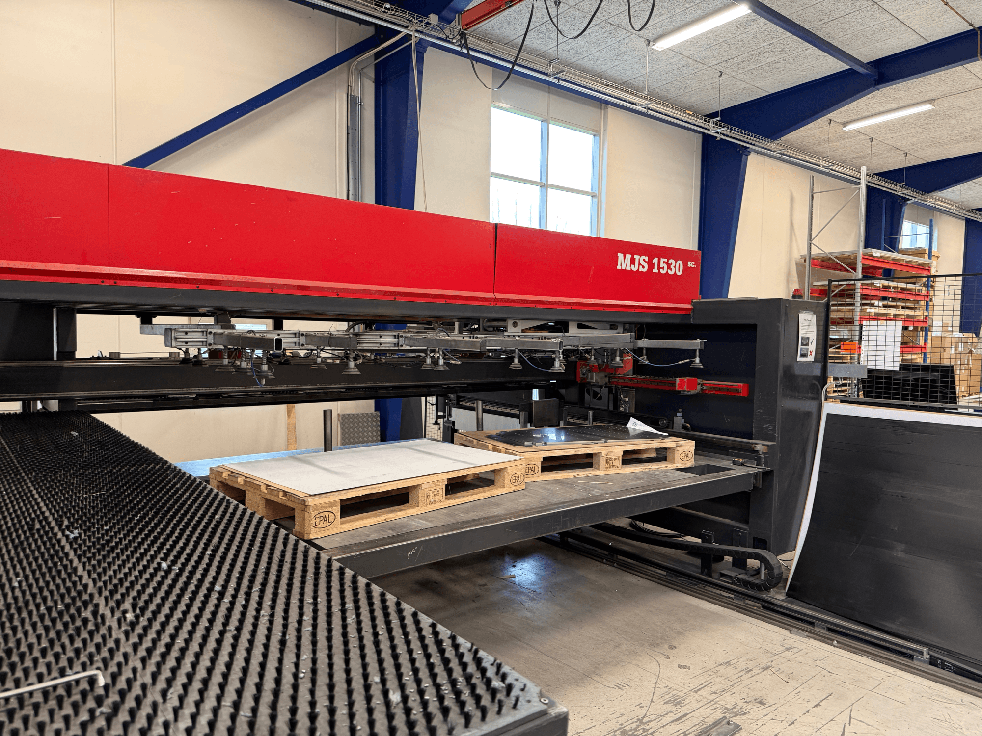 MJS 1530 CNC machine in a workshop, front view, with a wooden pallet holding a metal sheet on a raised platform.