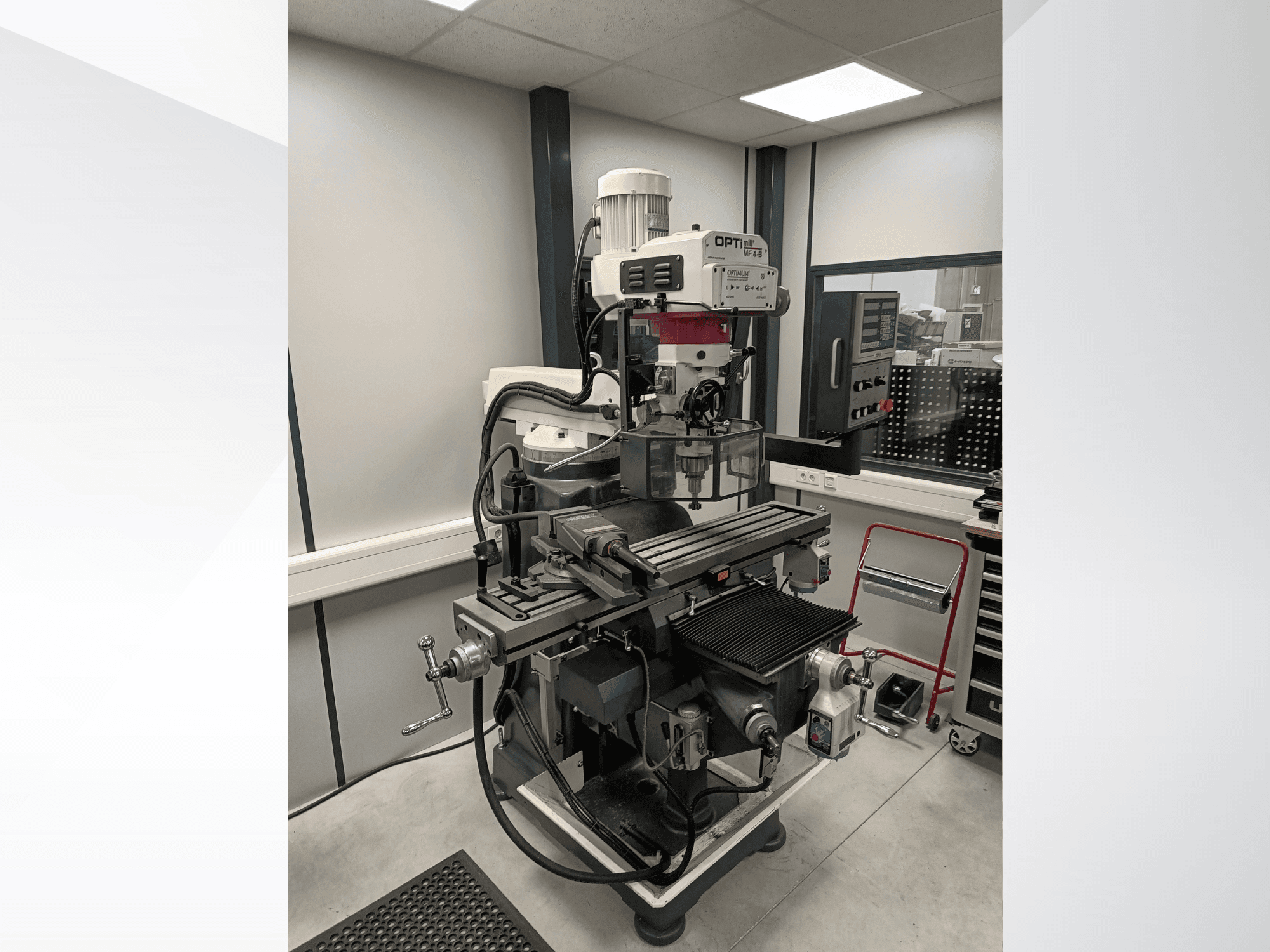 Optimum MF 4-B vertical machining center in side view, featuring a detailed work table, control panel, and motor.
