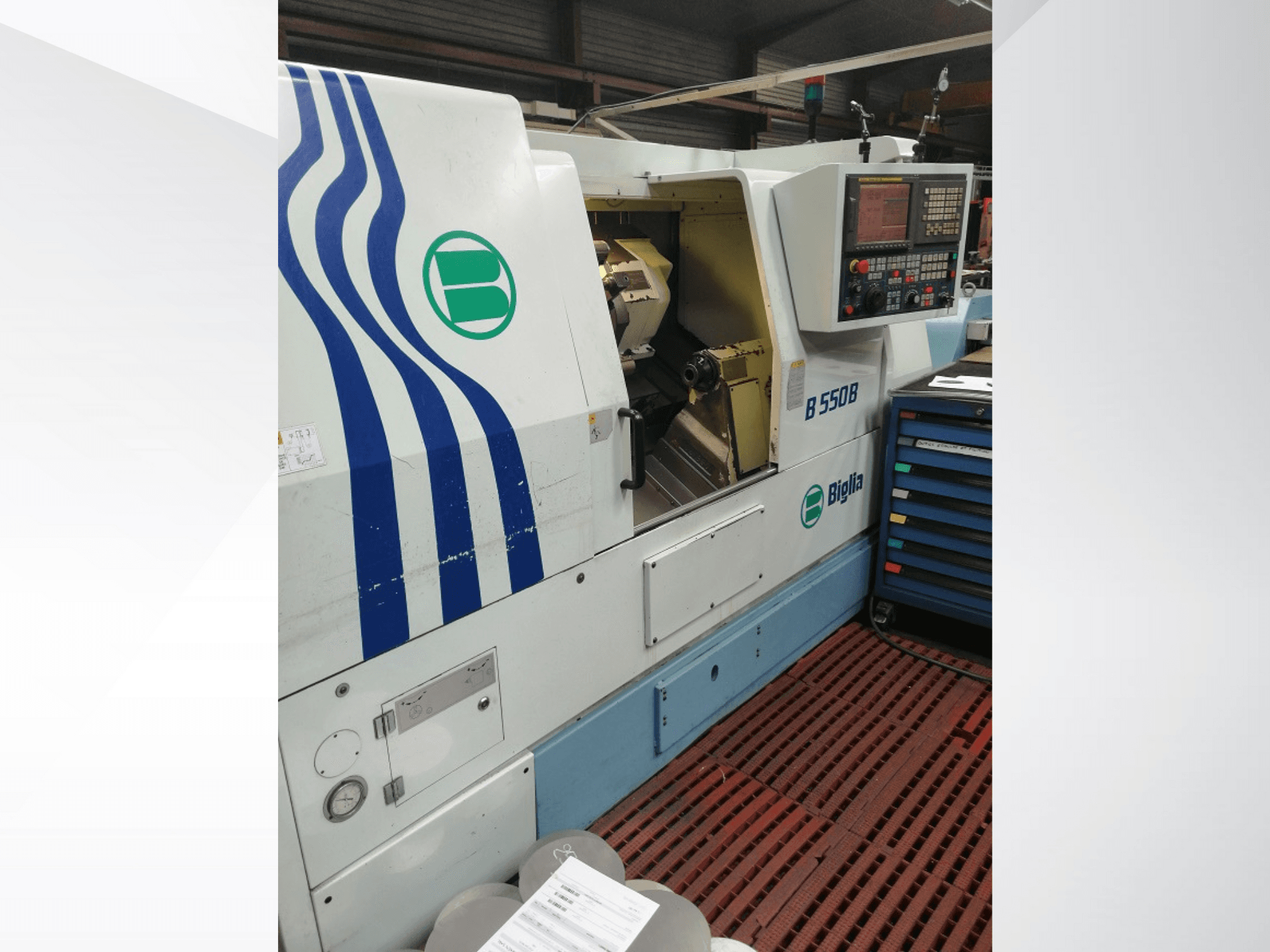 Biglia B 550 B CNC lathe machine shown from the front, featuring control panel, metalwork area, and colorful tool storage.