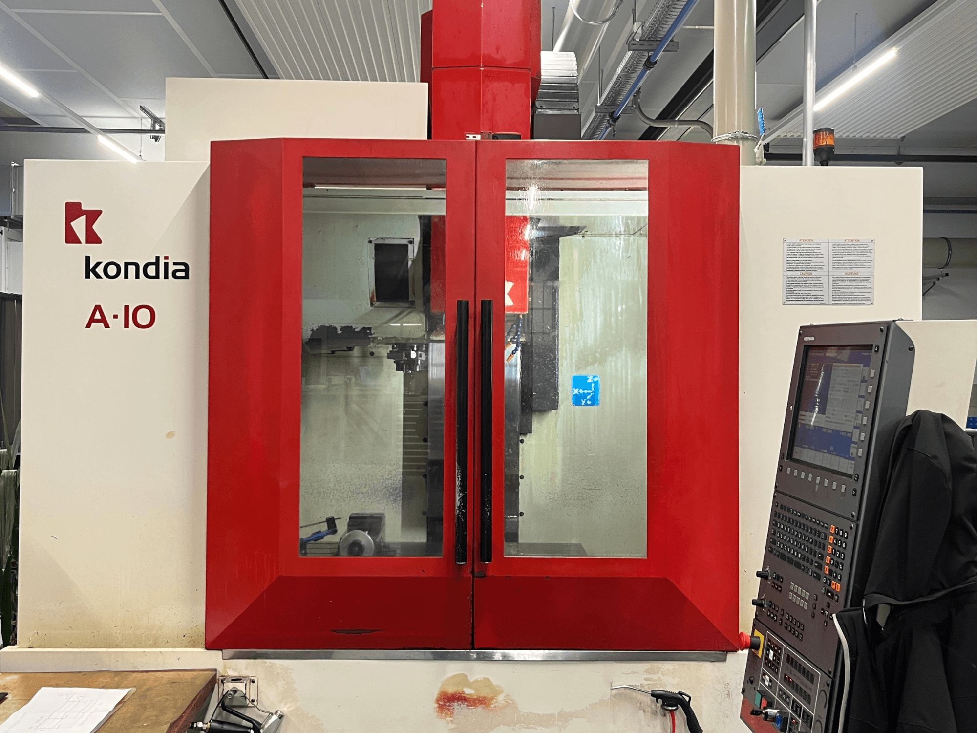 KONDIA A10 vertical machining center, front view; features red glass doors and control panel on the right.