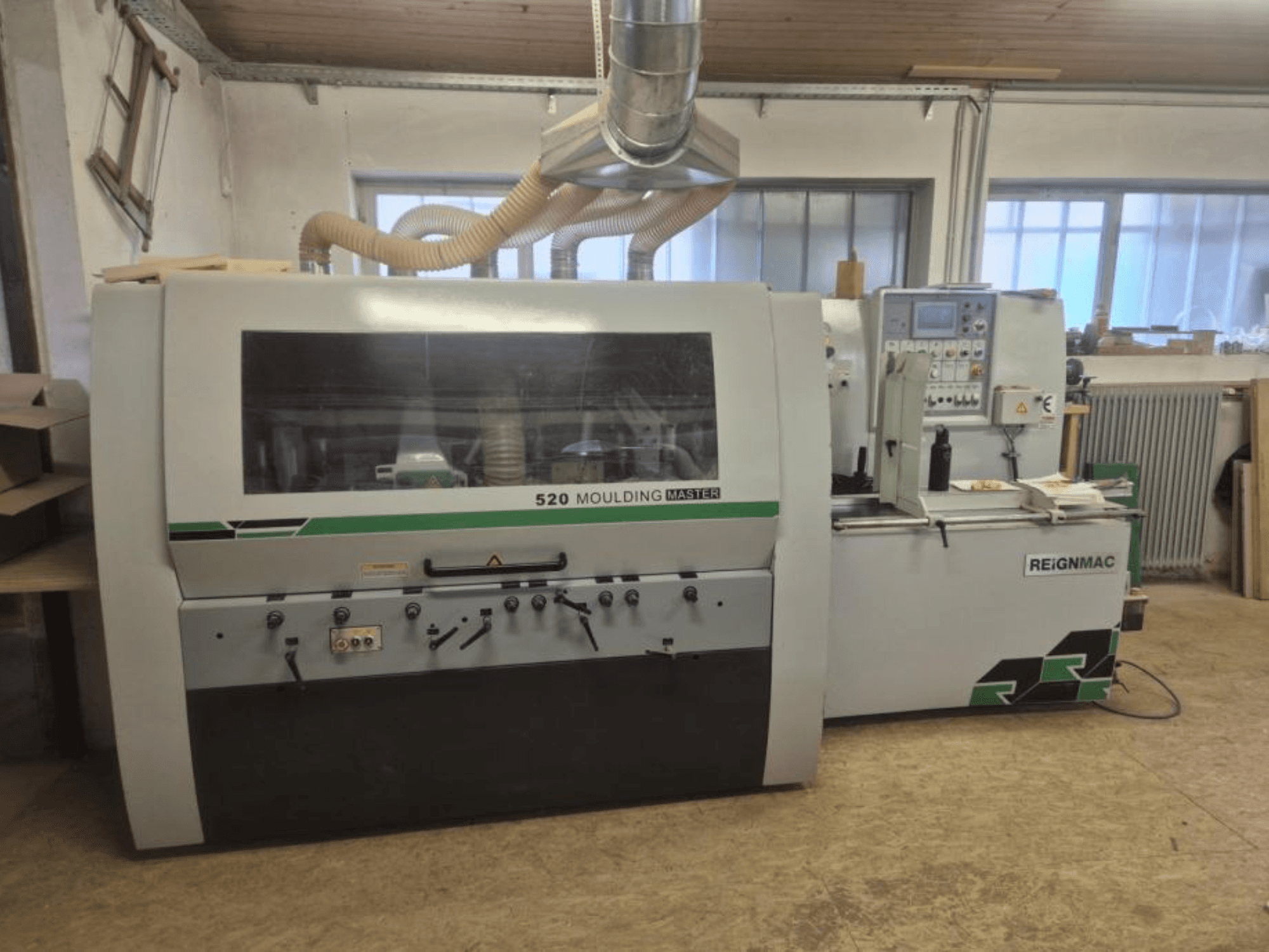 Front view of the REIGNMAC 520 MOULDING MASTER wood planer, showcasing control panel, feed rollers, and dust extraction system.