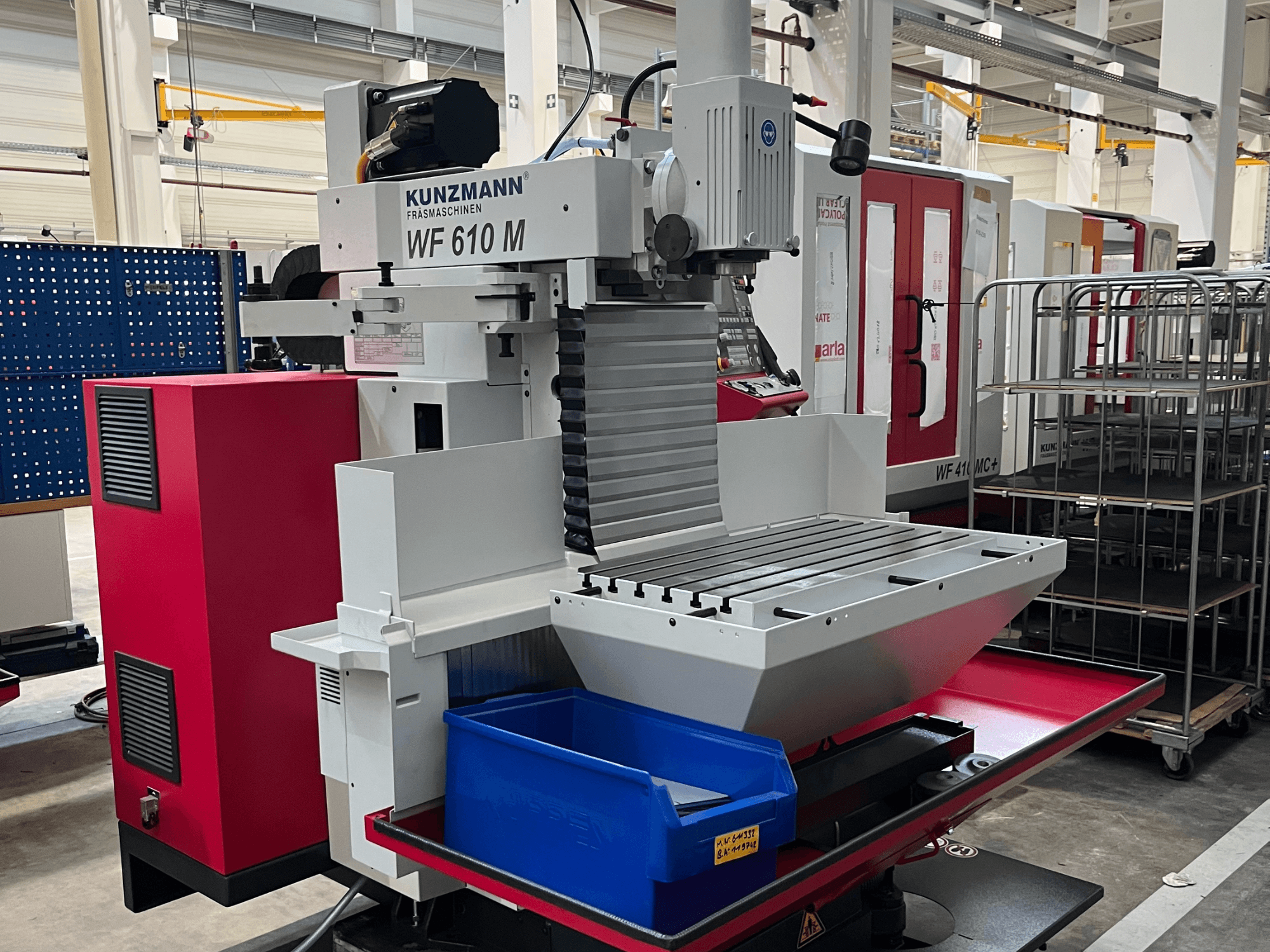 KUNZMANN WF 610 M universal machining center, front view, featuring a tool holder, horizontal table, and blue storage bin.