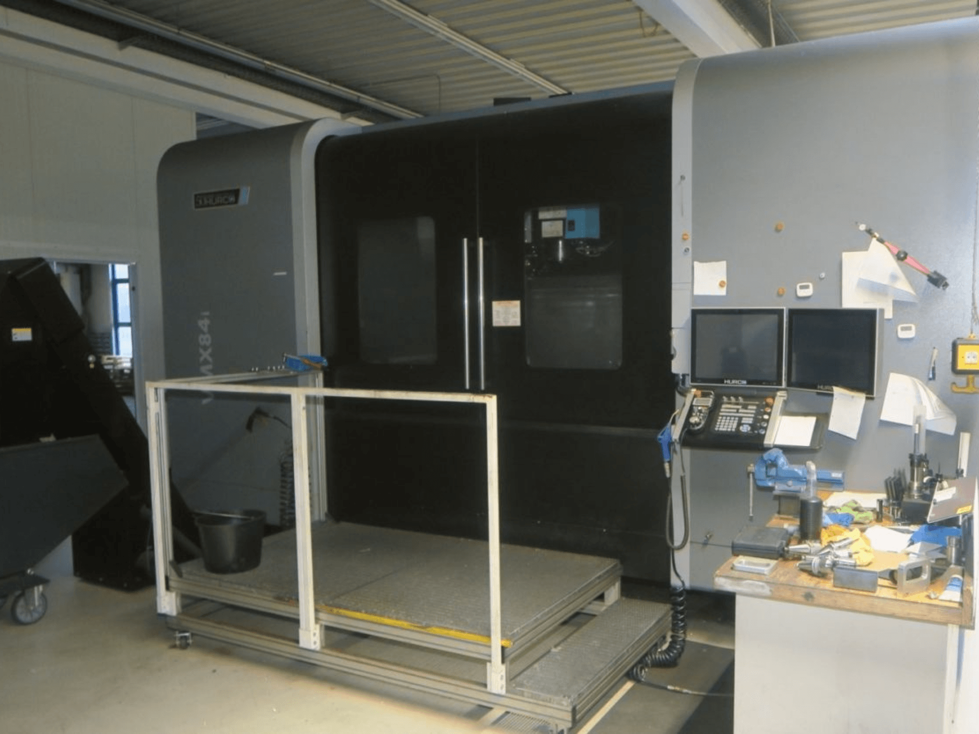 Hurco MX84 CNC machine in front view, showing dual monitors, control panel, and tool workspace with various tools.