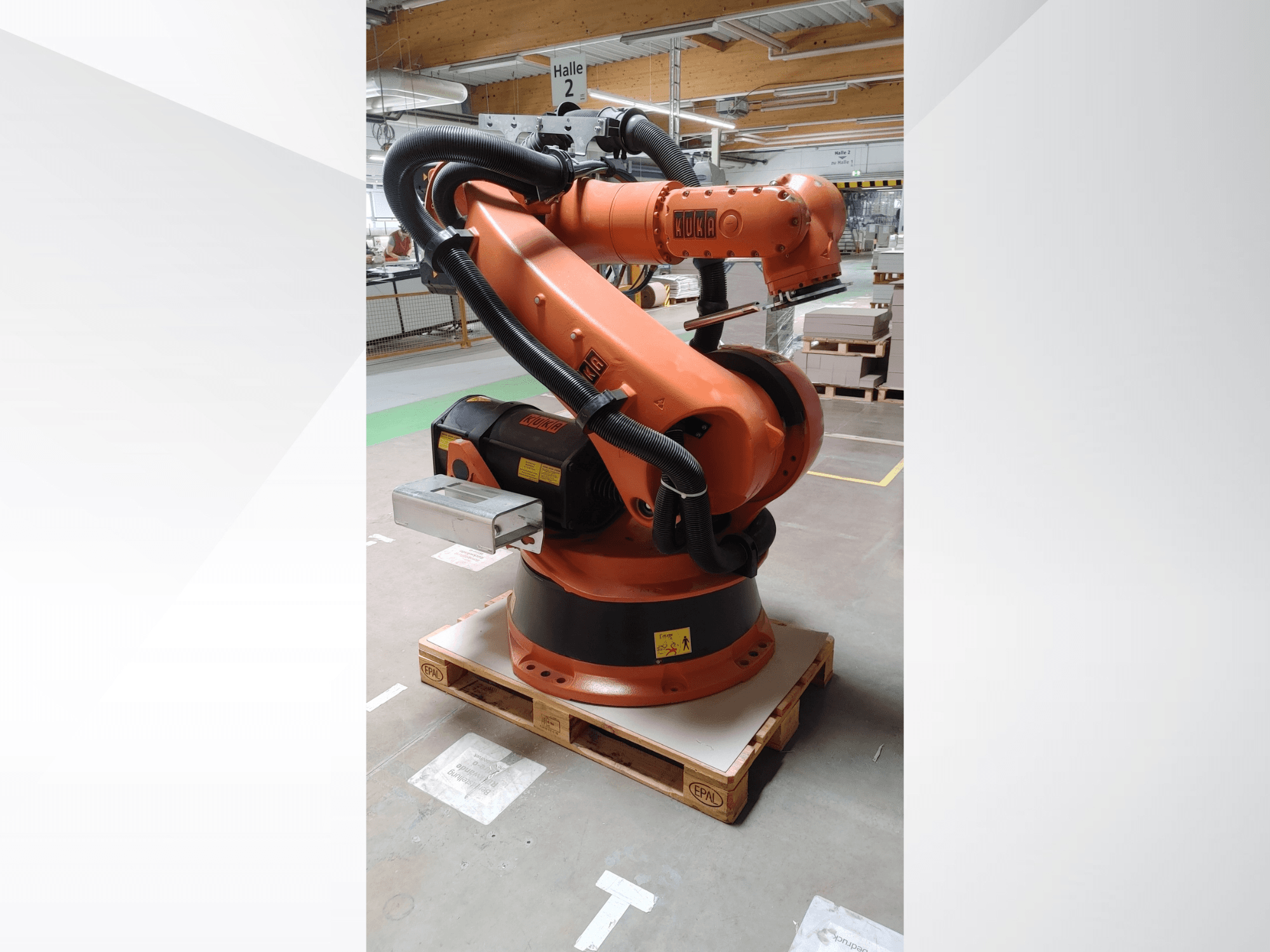KUKA KR140-3 COMP robot arm in orange, front view on a wooden pallet, featuring a curved arm and control box.