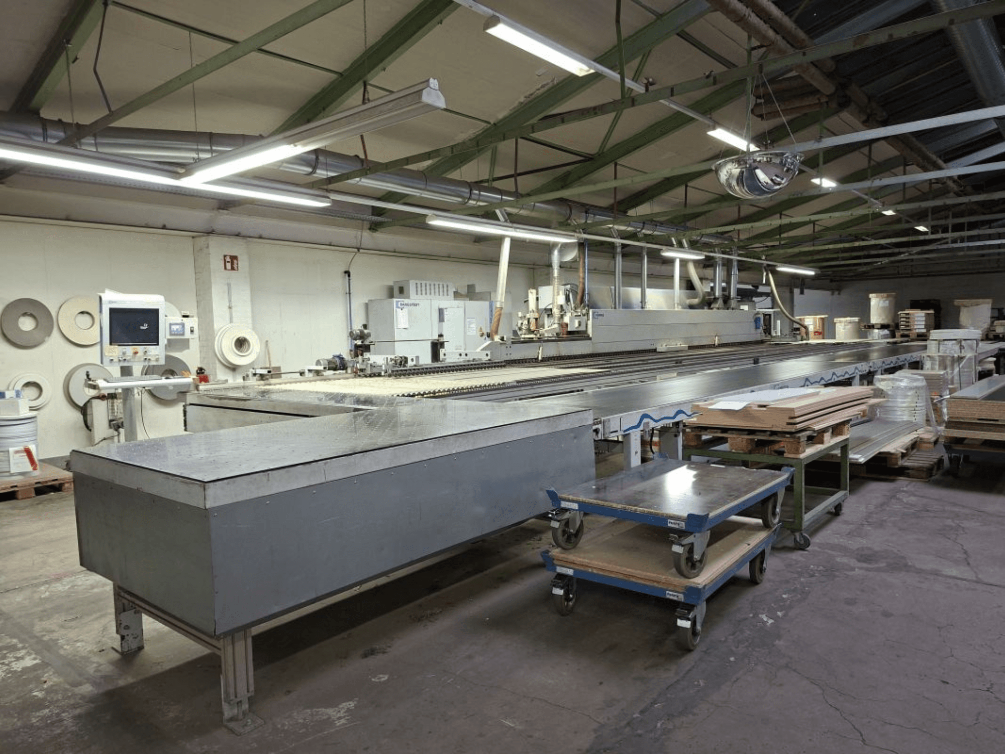 HOMAG Optimat KAL 330 edgebander seen from a side view, featuring a long conveyor table and control panel in a workshop setting.