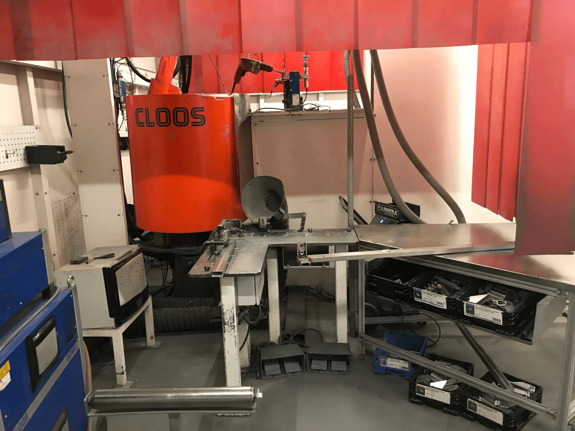 Welding Shop System by DESSAUER, front view showing robotic arm, metalwork surface, and storage areas in a shop environment.