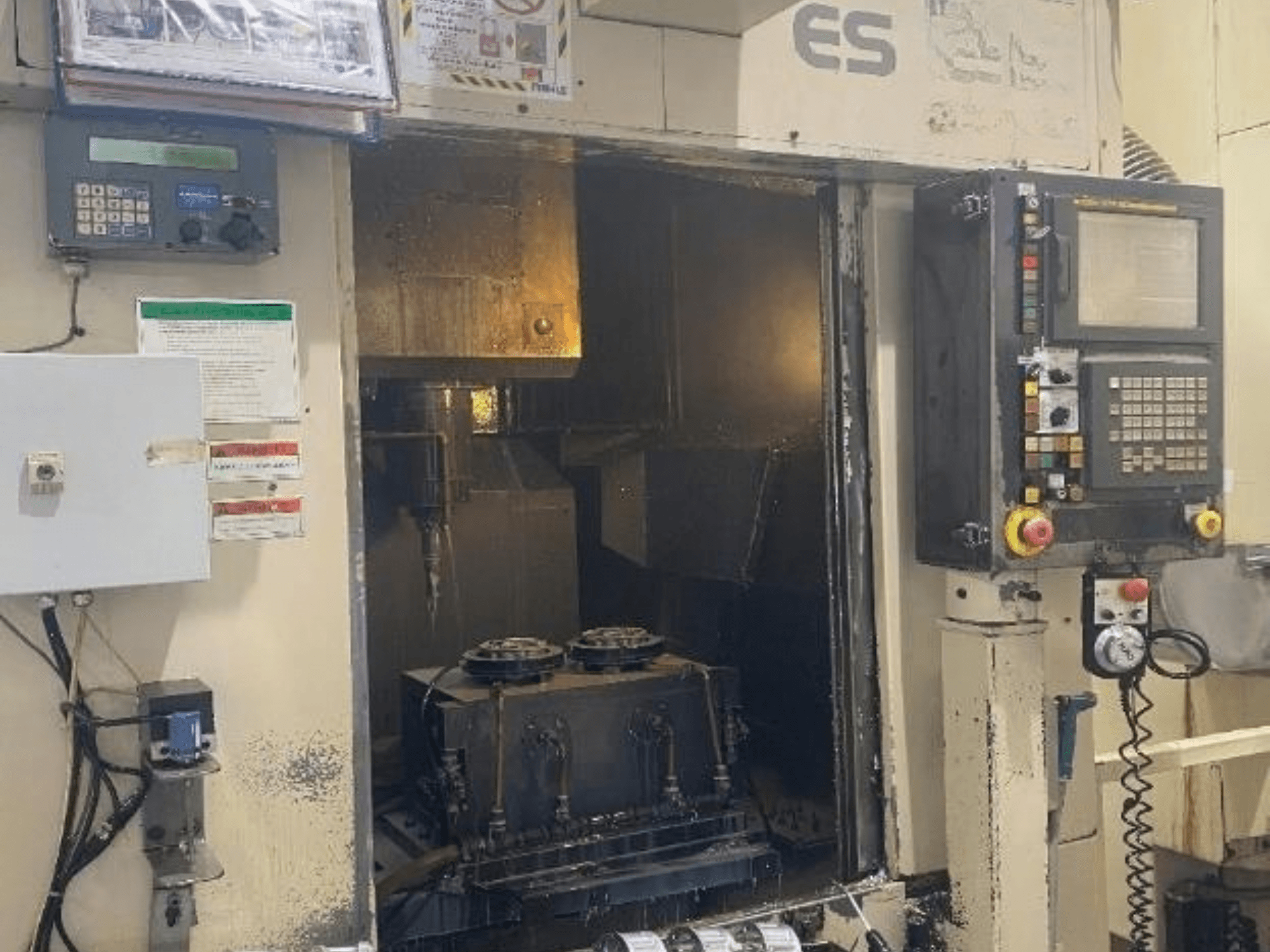 Front view of the Enshu ES450 vertical machining center, featuring controls, interior view, and tool holding area.