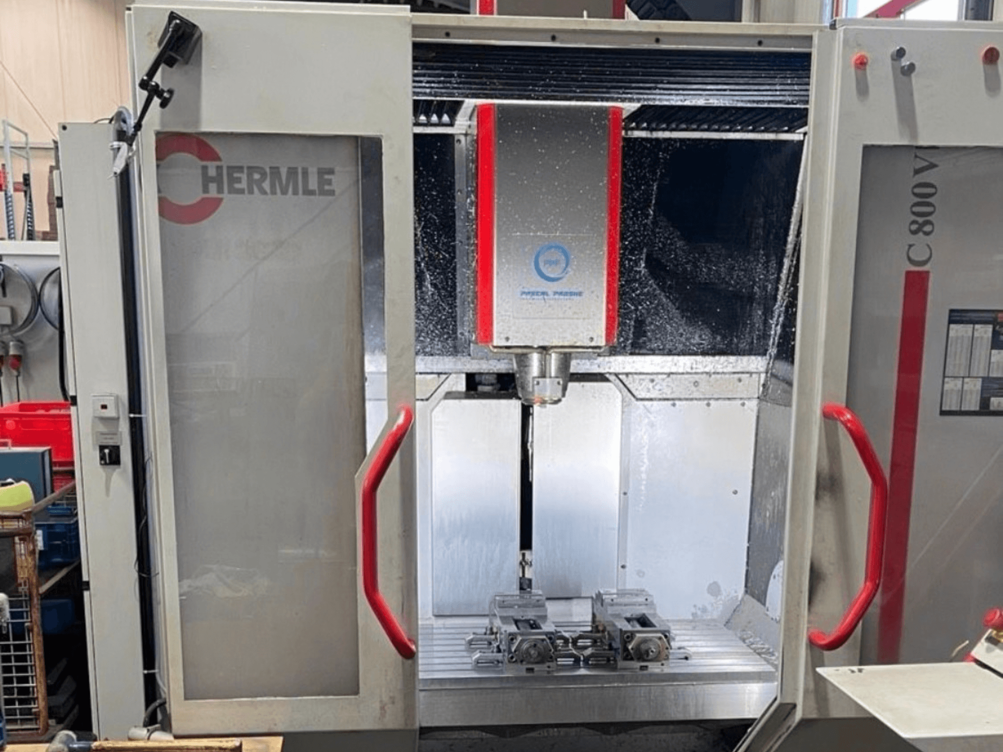 HERMLE C800V vertical machining center, front view displaying machining area with workpieces and liquid coolant.