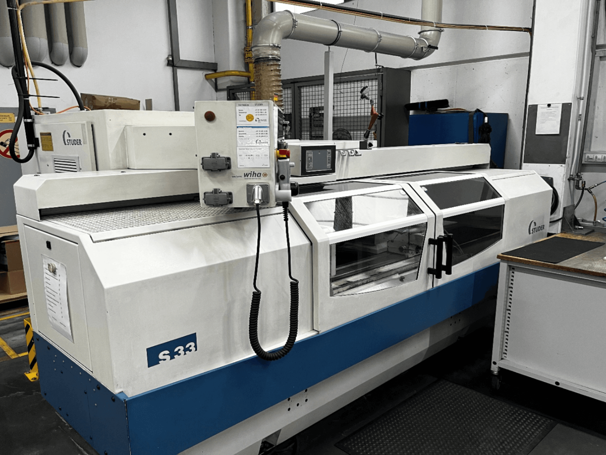 STUDER S33 CNC cylindrical grinding machine, front view; features control panel and glass safety doors. Industrial setting.
