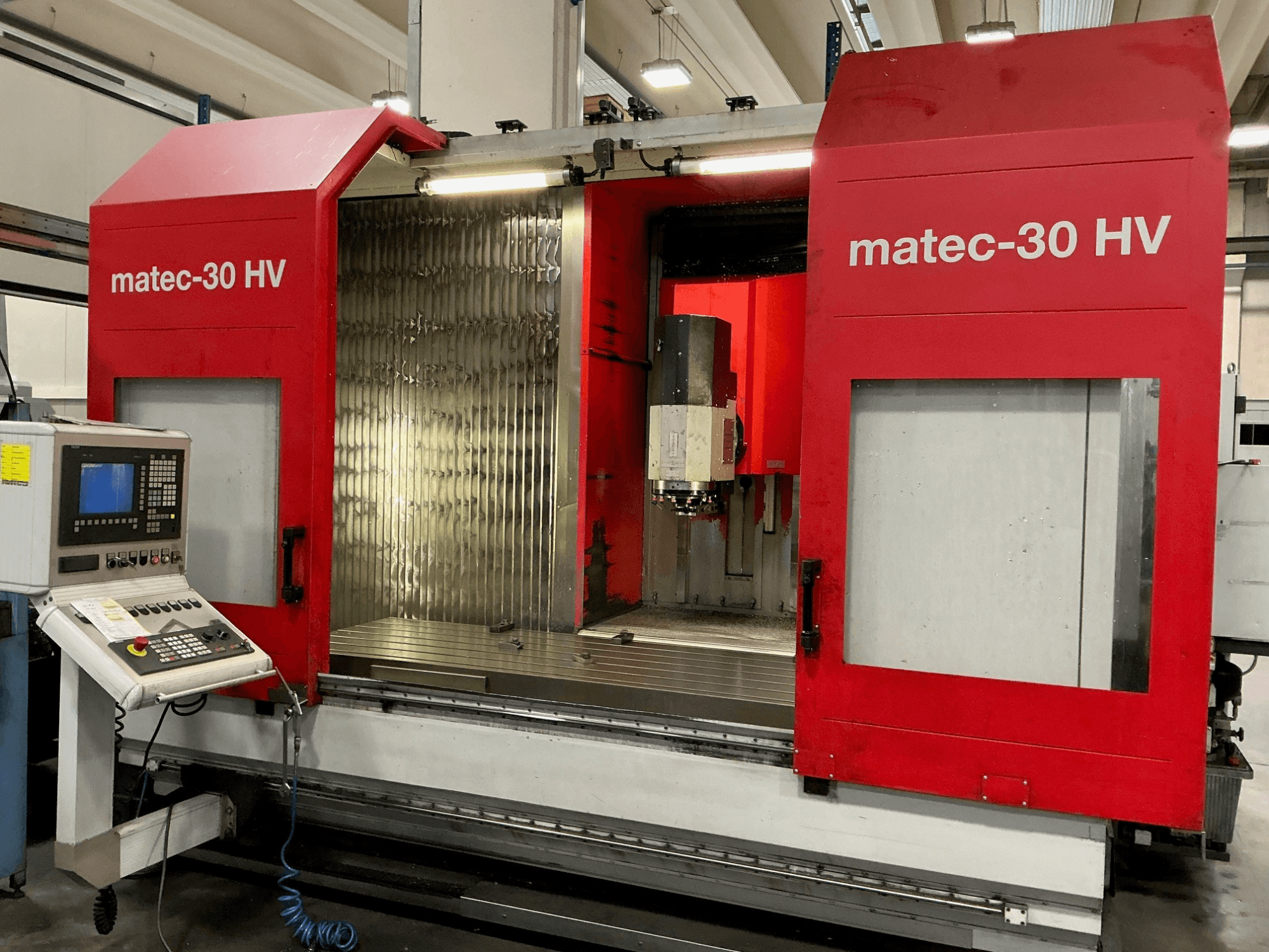 Red Matec 30 HV vertical machining center in front view, featuring control panel and open doors revealing cutting area.