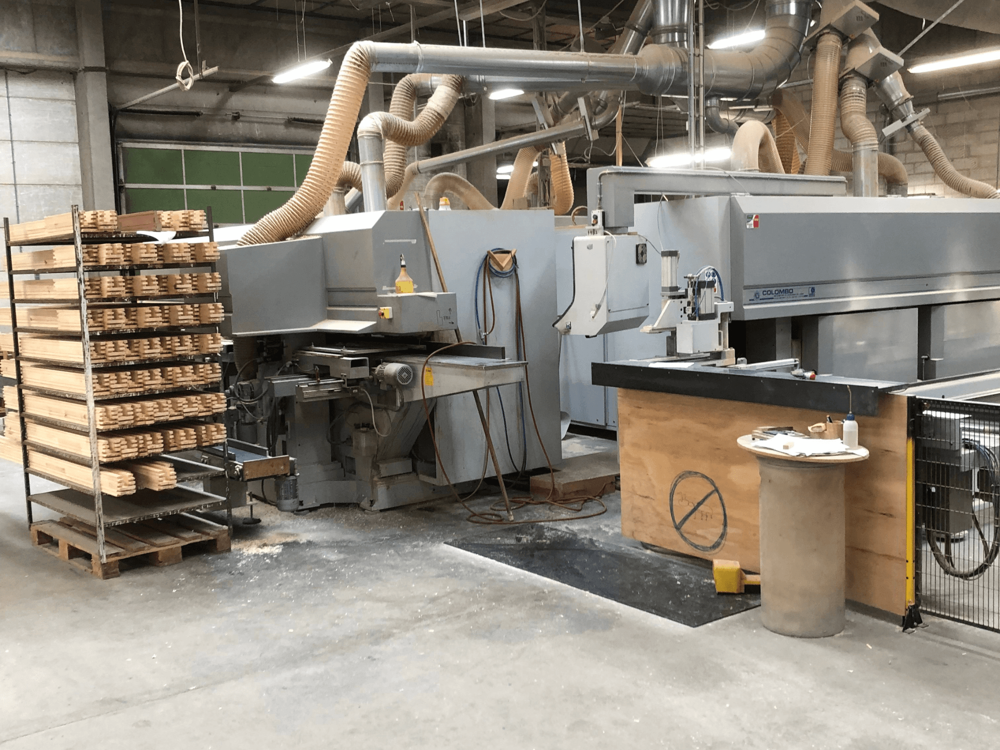 Colombo AM 60 spindle moulder, side view, with stacked wood pieces nearby and dust collection system visible.