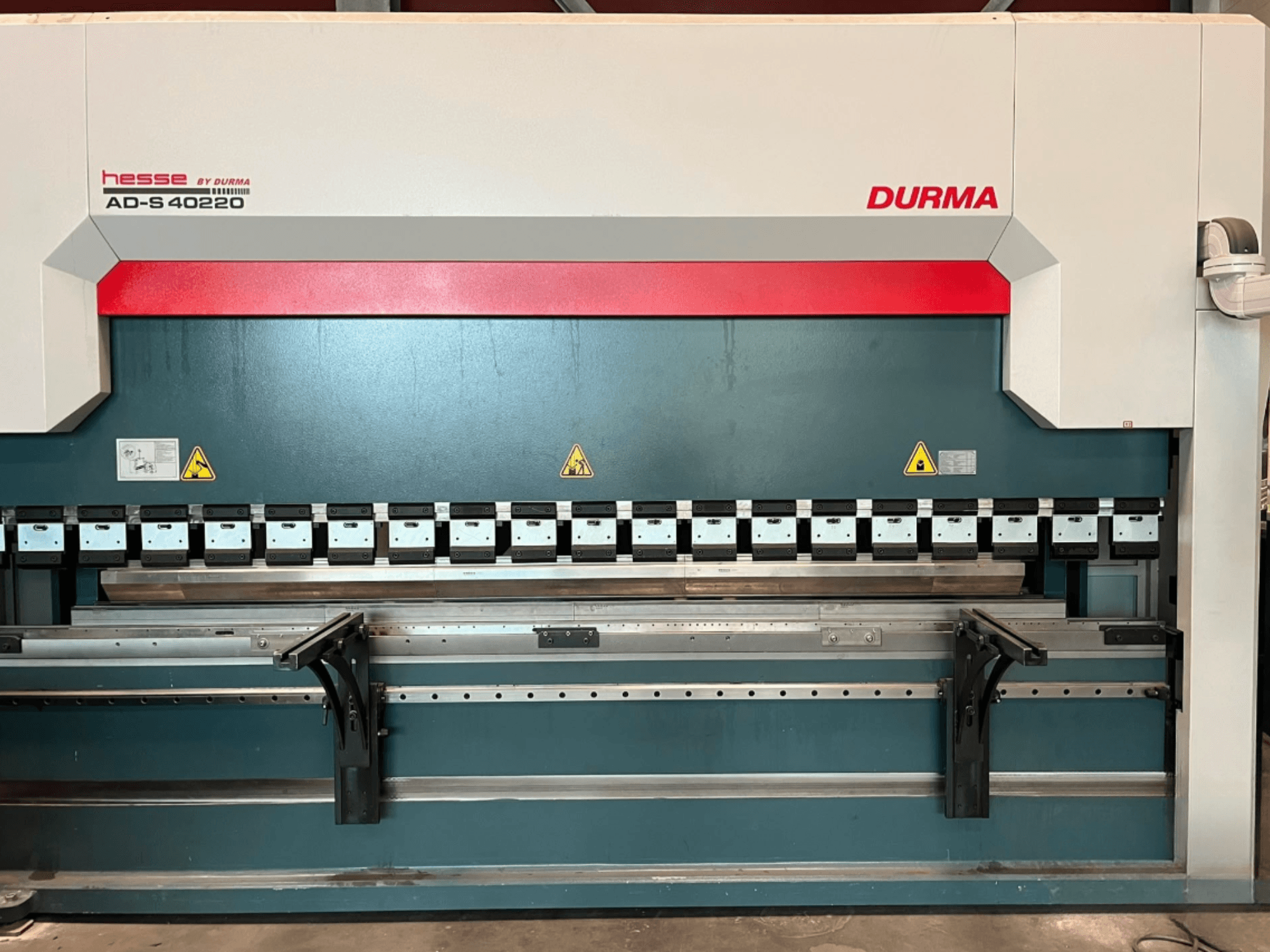 Durma AD-S 40220 press brake viewed from the front, featuring multiple bending tools and safety labels.