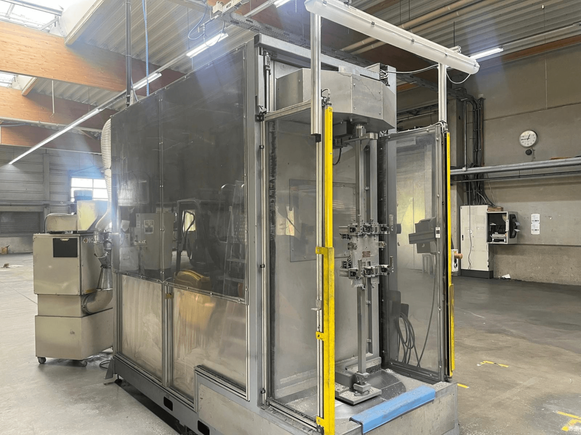 M.A.I. ASD 1 machine tool shown from a side view, featuring a transparent enclosure and front access controls in a workshop.