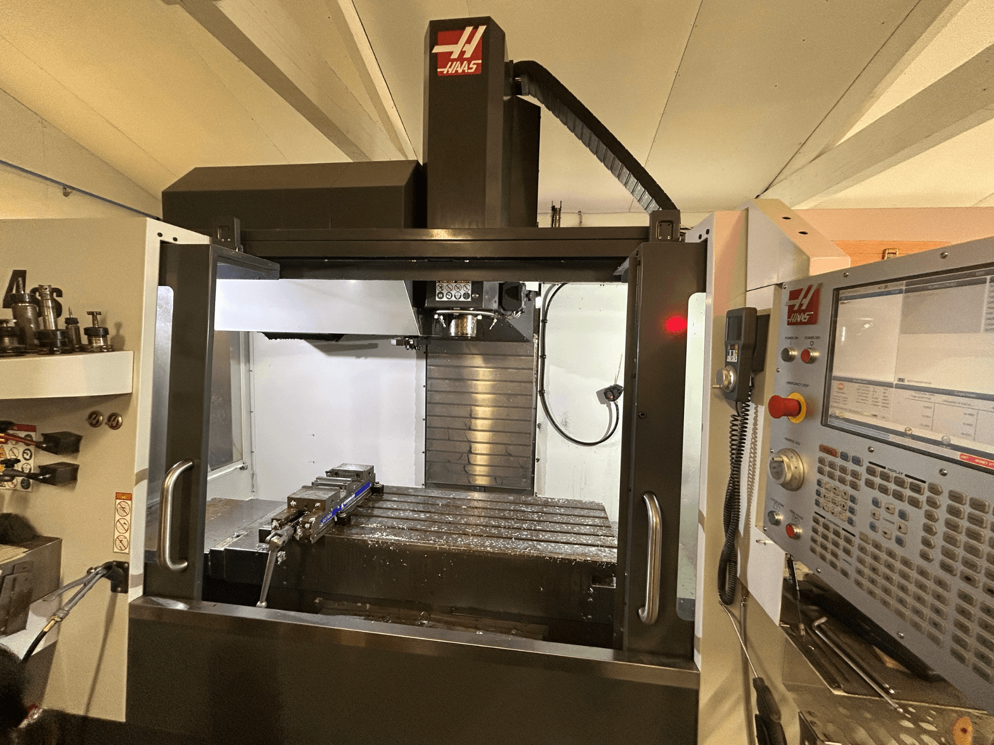 HAAS VF-4SS vertical machining center, front view, showcasing control panel, tool holder, and work area with metal shavings.