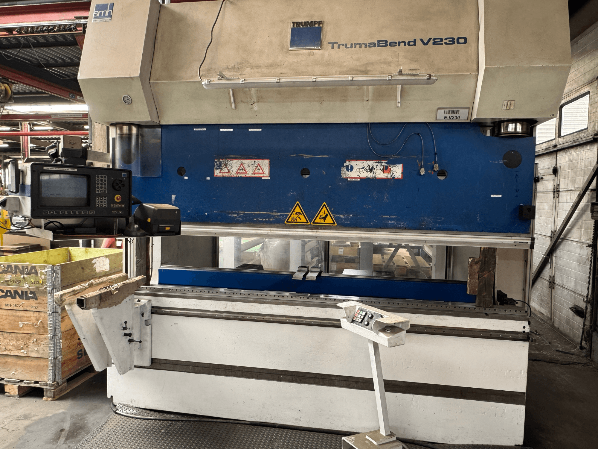 TRUMPF TrumaBend V230 press brake, front view with control panel, warning labels, and a workpiece support arm visible.