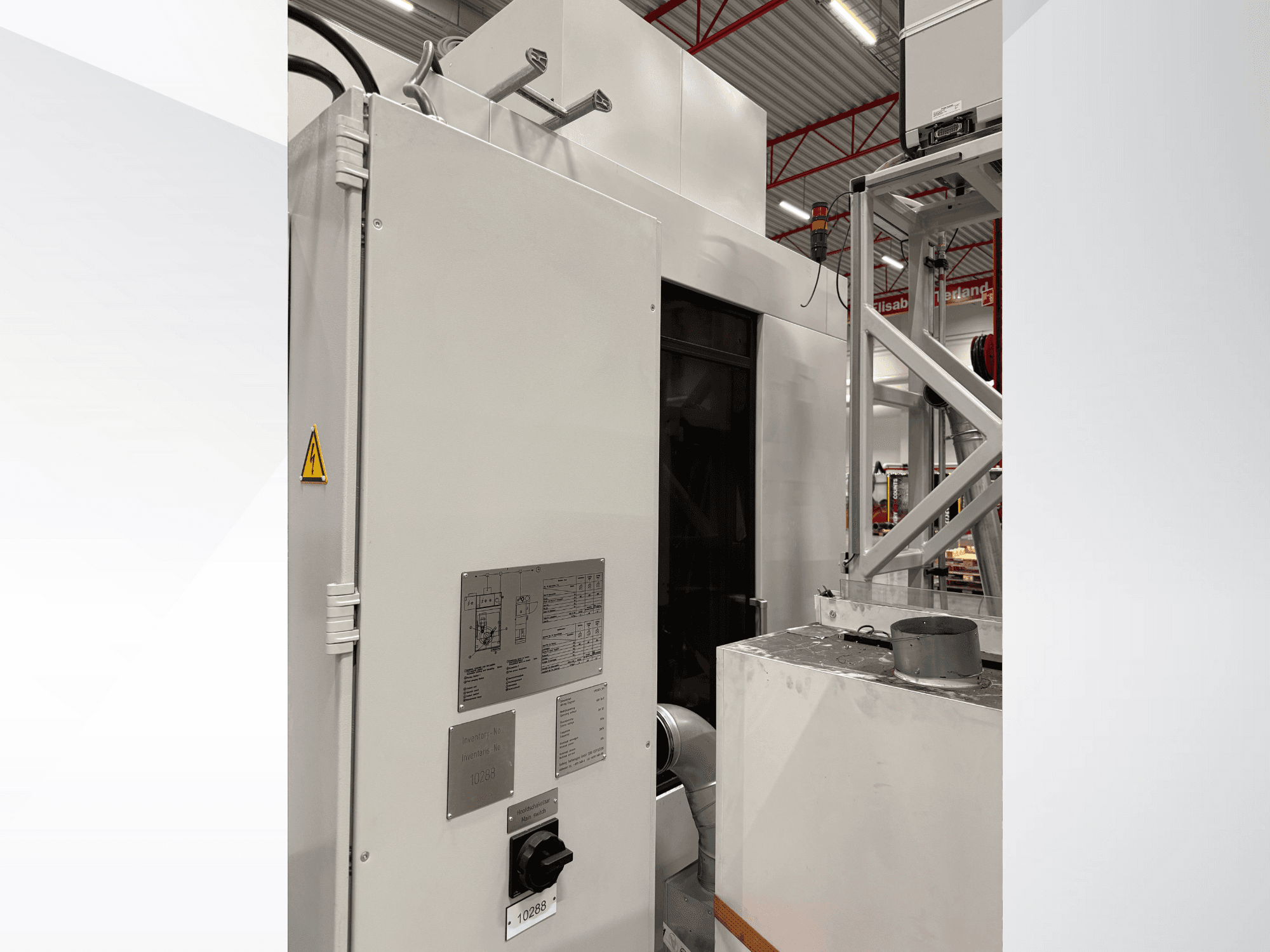 Side view of a white industrial machine with control panel and warning label, part of an automated system.