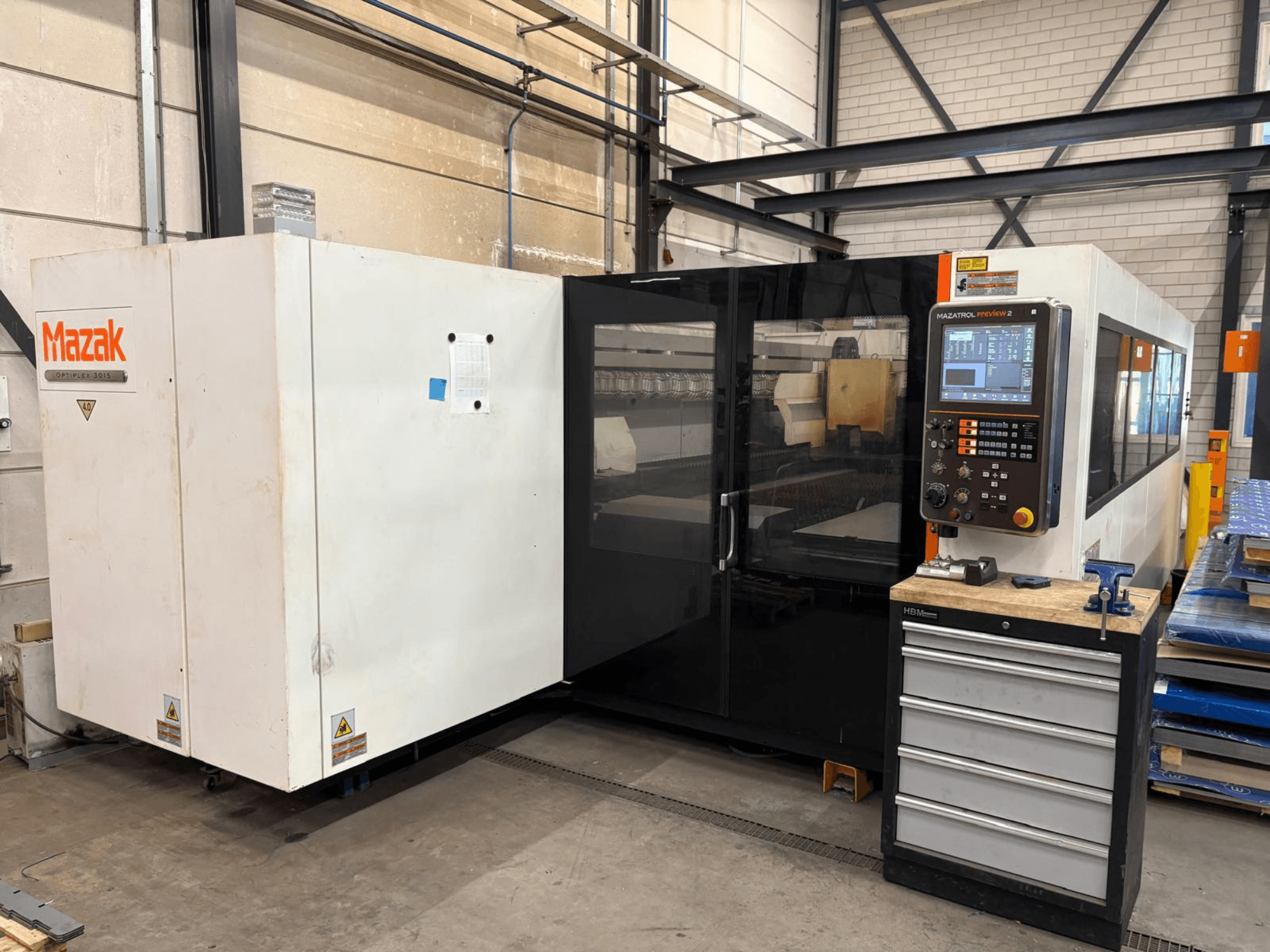 Mazak Optiplex 3015 CO2 laser cutting machine, front view, showing control panel and industrial setting.