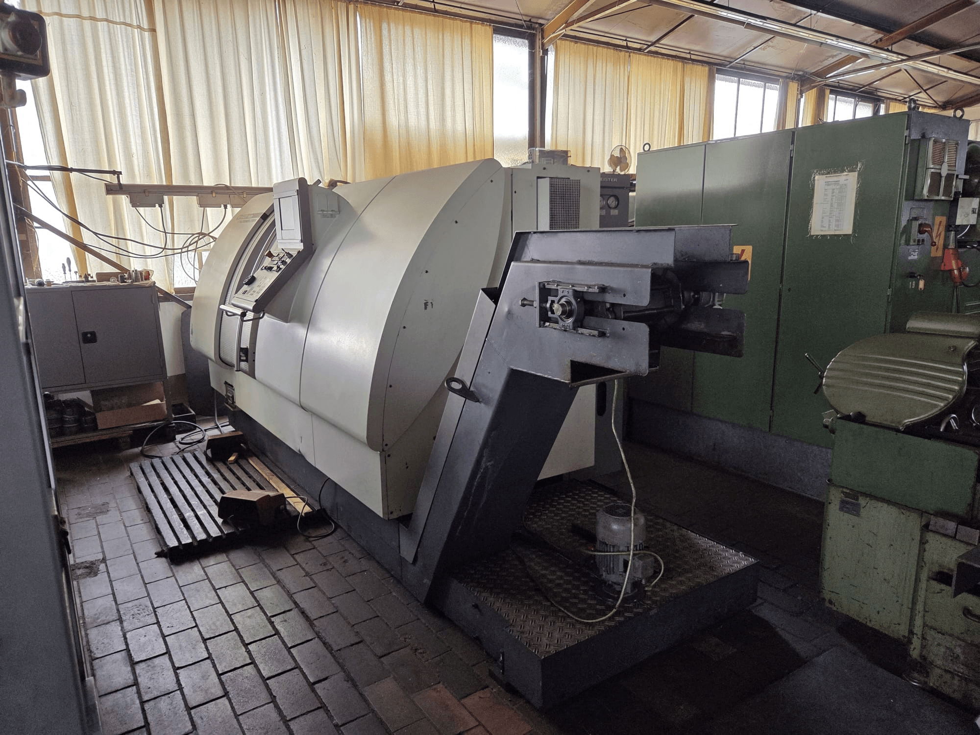 Gildemeister CTX 400 twin turn-mill centre, side view, showcases control panel, large chassis, and adjacent machinery in workshop.
