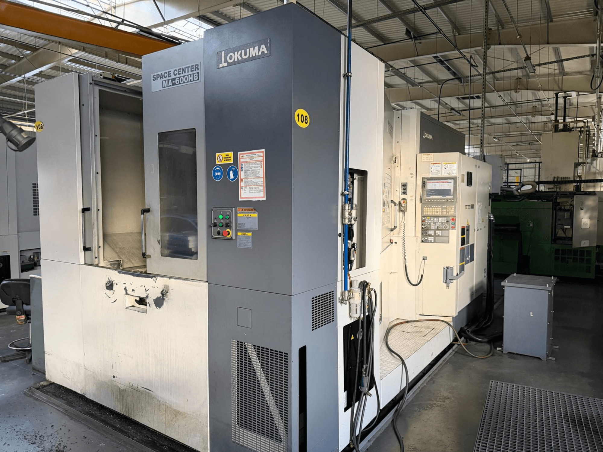 Okuma MA-600 HB horizontal machining center, front view, showcasing control panel and cutting area with visible wear marks.