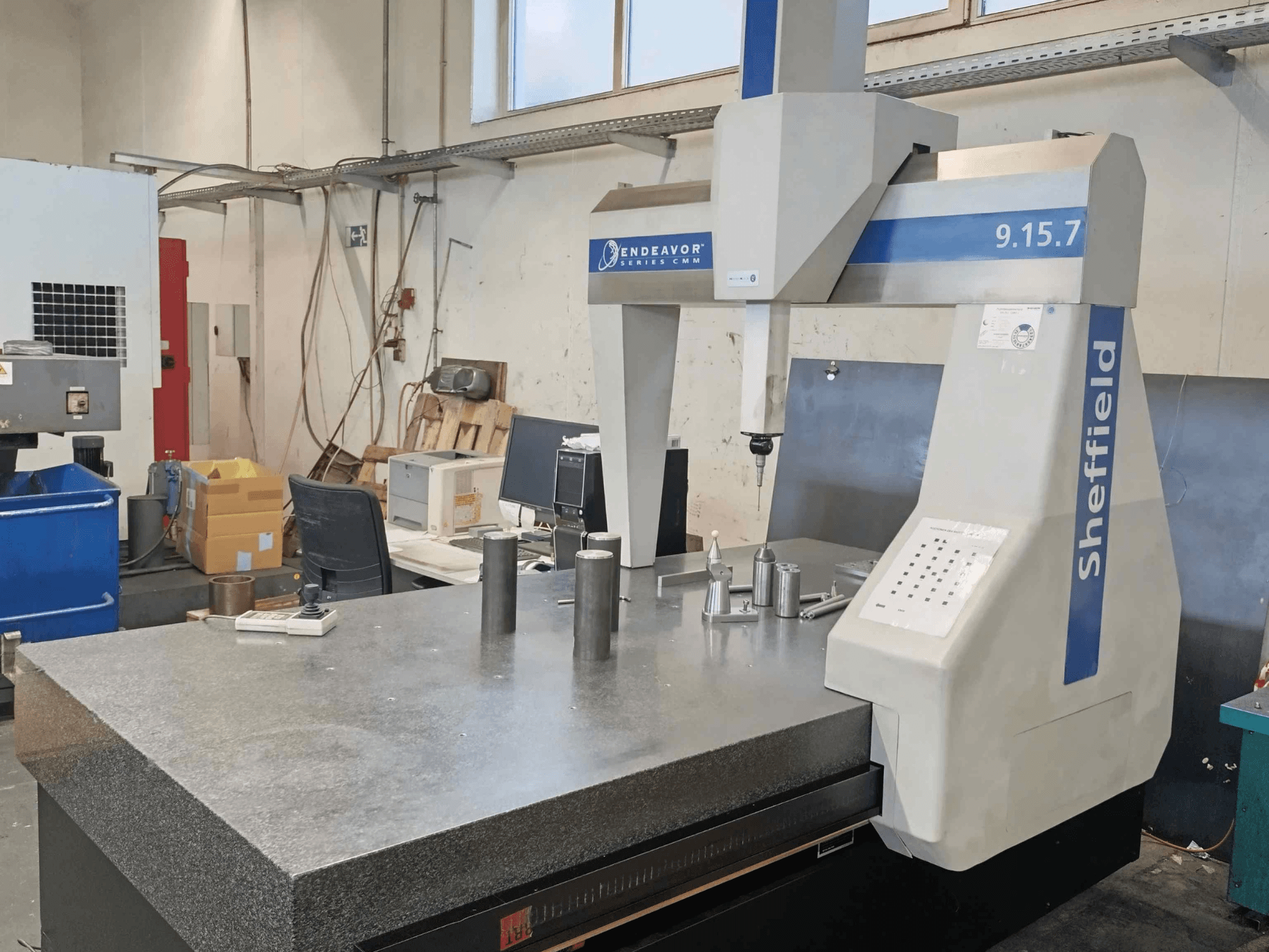 Coordinate Measuring Machine Sheffield Endeavor 9.15.7 in a workshop, featuring a granite table and metallic workpieces.