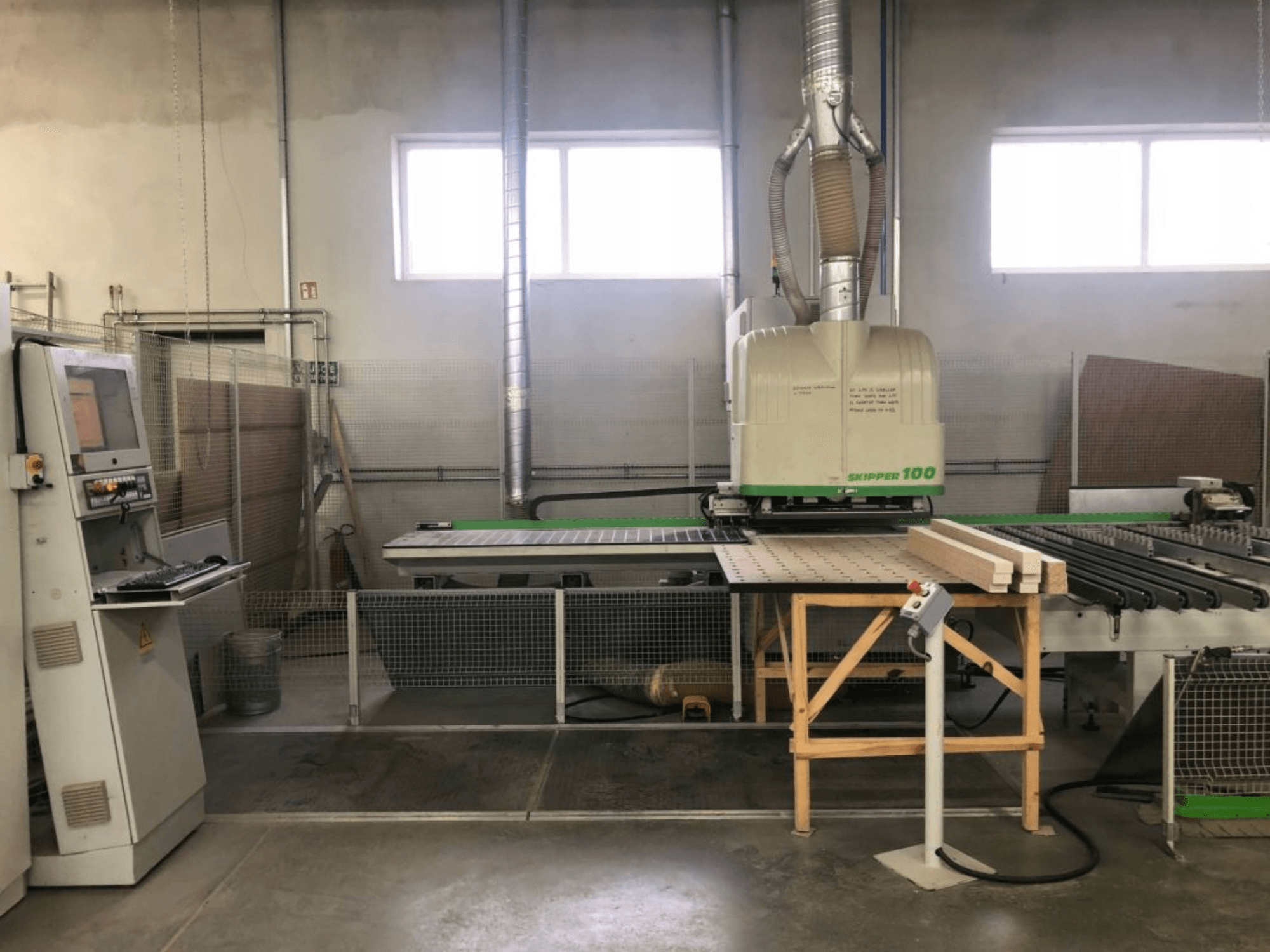 BIESSE SKIPPER 100 CNC processing center in a workshop, front view shows machine with control panel and wood on the table.