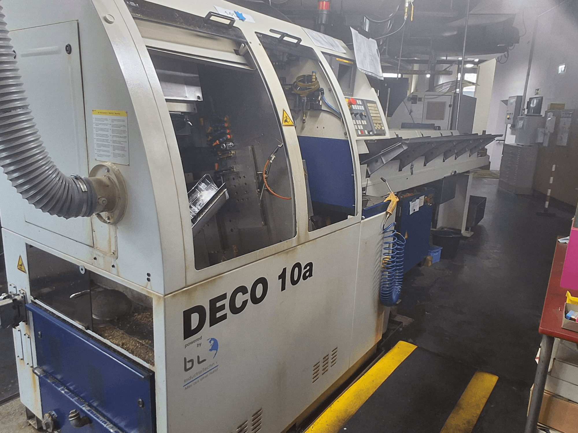 Swiss Type Turning Machine TORNOS DECO 10a, front view; features a control panel, visible mechanisms, and a dust extraction tube.