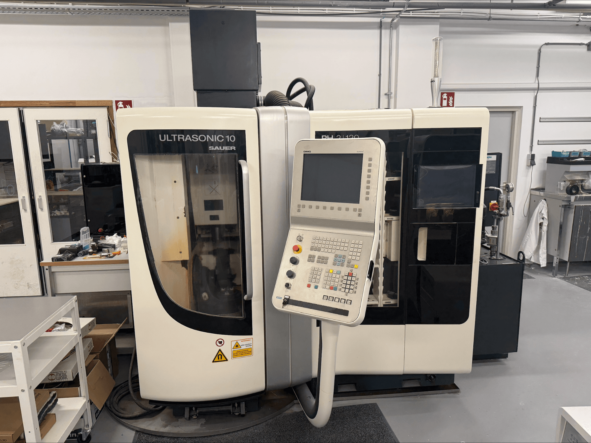 DMG Sauer Ultrasonic 10 + PH 2 | 120 vertical machining center, front view, featuring control panel and large viewing window.