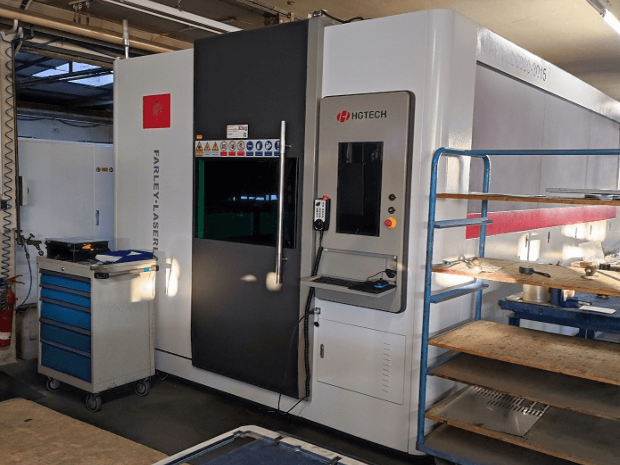 HGTECH Marvel 6000-3015 fiber laser cutting machine, front view with control panel and adjacent storage.