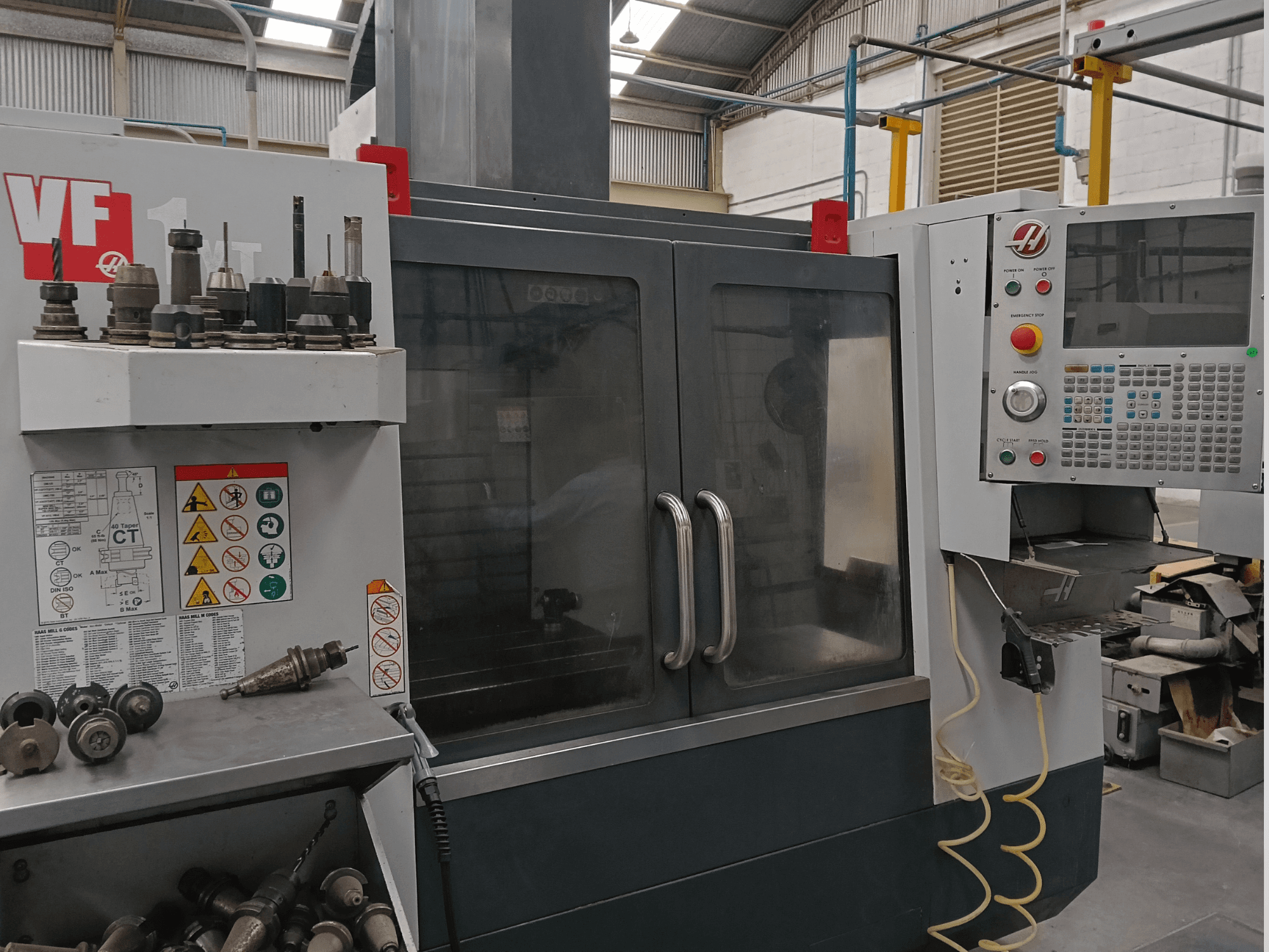 HAAS VF-1YT-3 Vertical Machining Centre in front view, showcasing controls, tool holders, and visible safety labels.