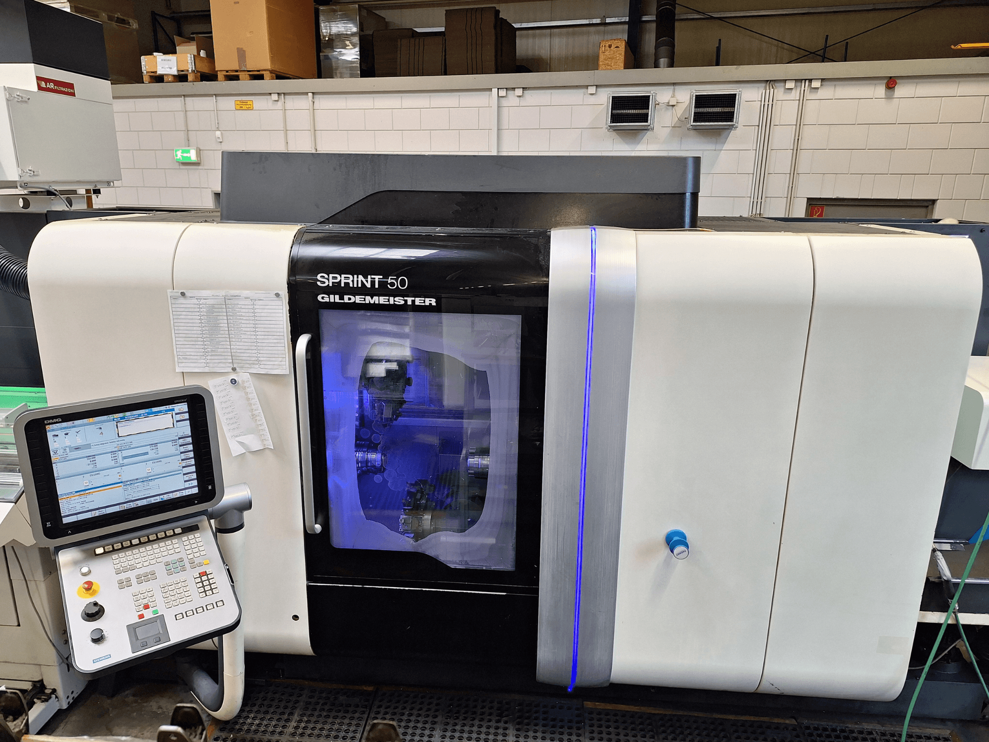 DMG Sprint 50 2T horizontal turning machine, front view, featuring control panel and transparent casing showcasing machinery inside.