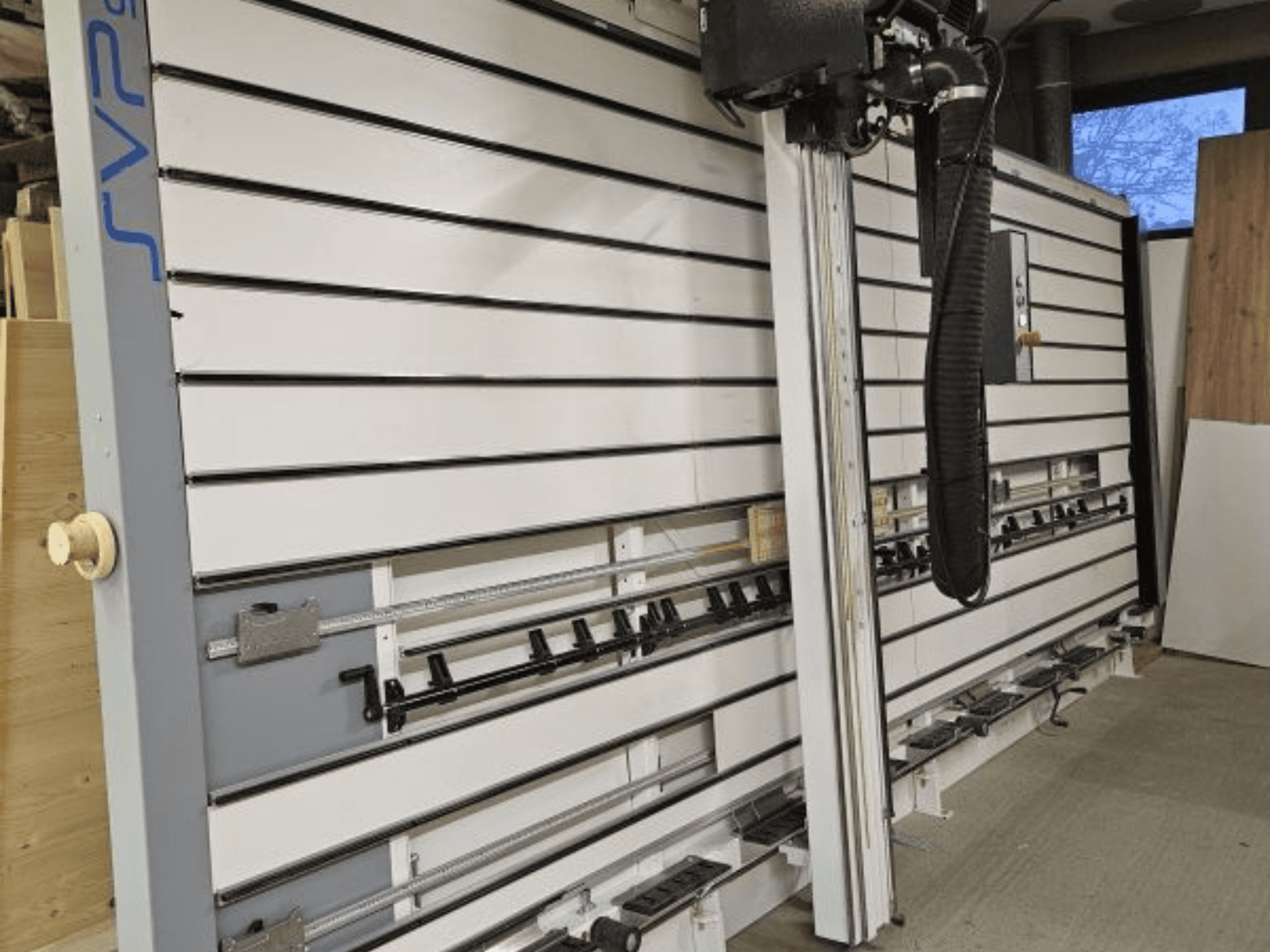 SVP sliding panel saw in a workshop, front view, featuring adjustable tracks and an overhead dust extraction system.