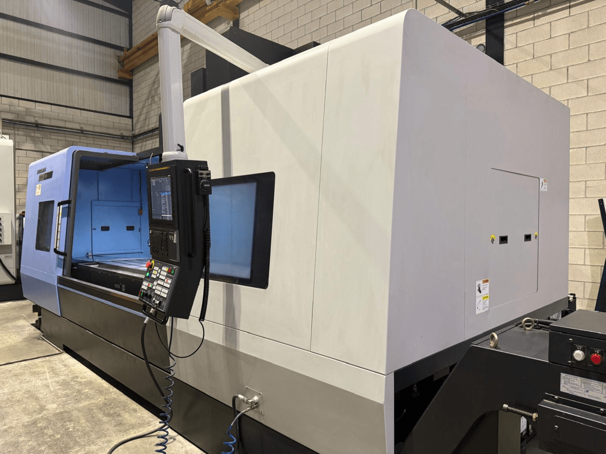 Industrial CNC lathe, blue and gray exterior, front view; features control panel with buttons and display for precise operations.