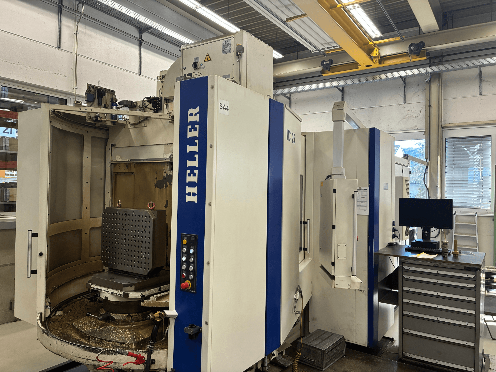 Horizontal machining centre HELLER MCi 25, front view; features a worktable with a hexagonal fixture and control panel visible.