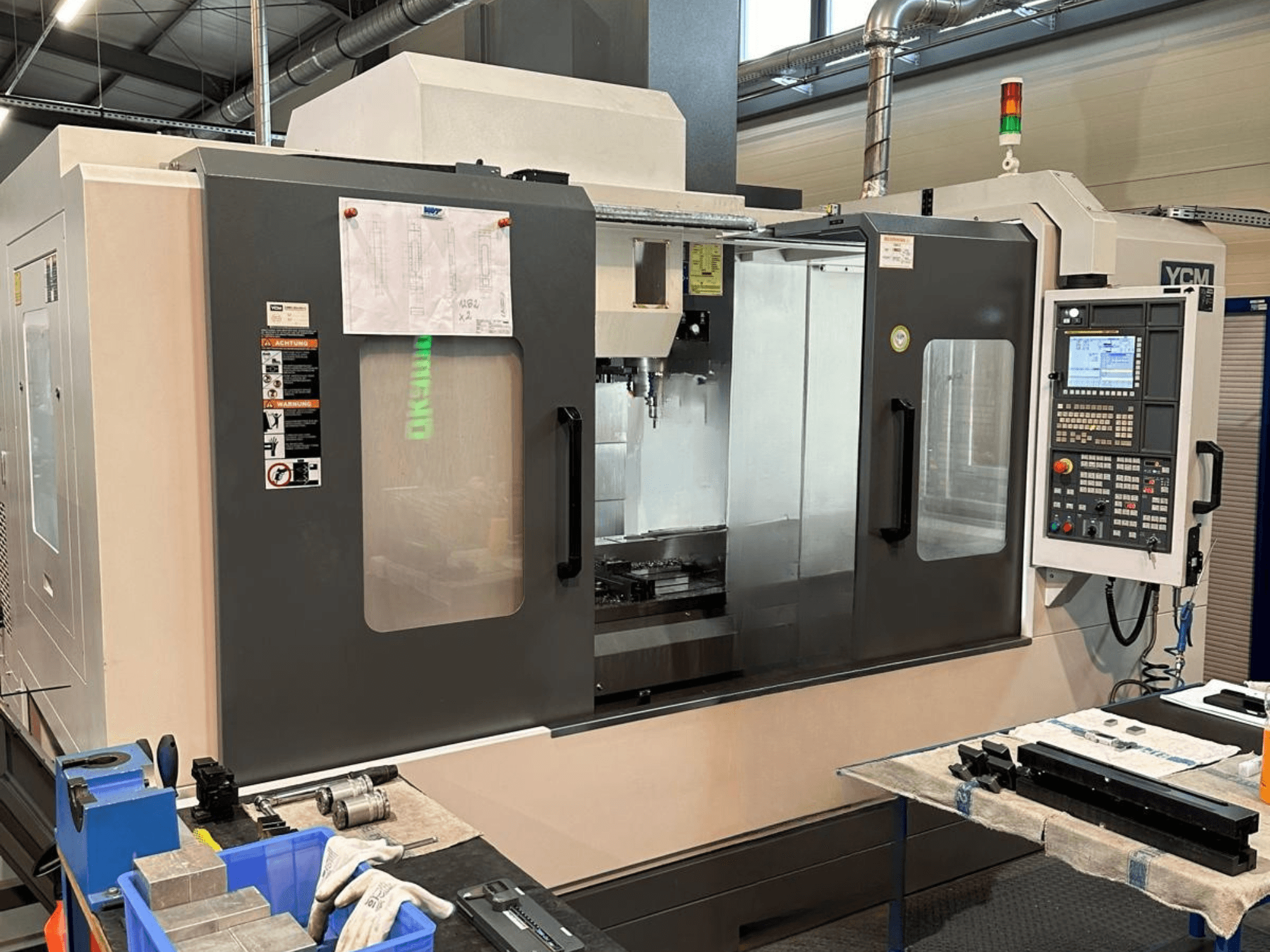 YCM NSV 156 A Vertical Machining Centre front view, featuring control panel, tool compartment, and surrounding work area.