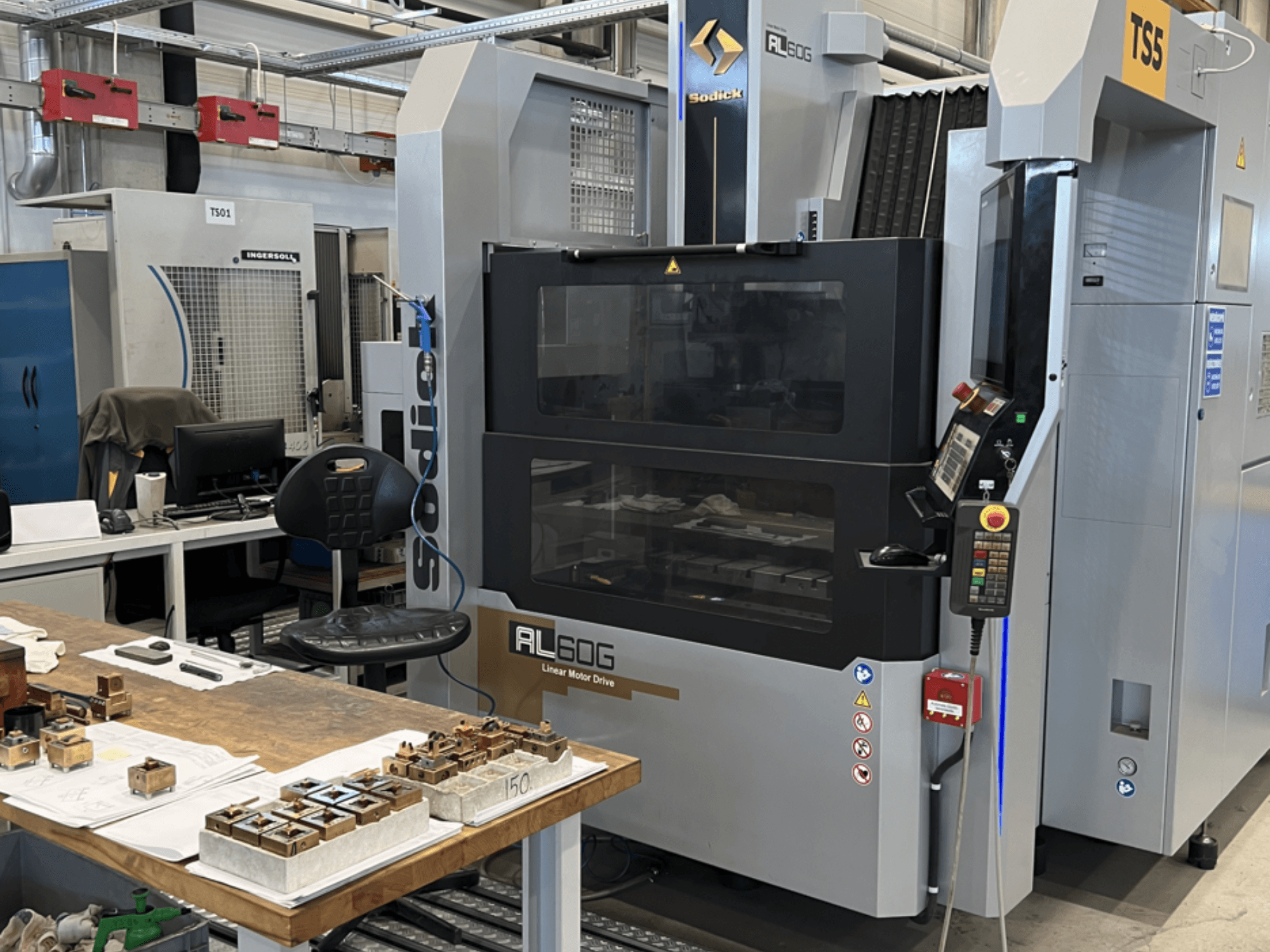 Sodick AL60G Die-Sinking EDM Machine; front view showing controls, window, and workspace with various metal parts.