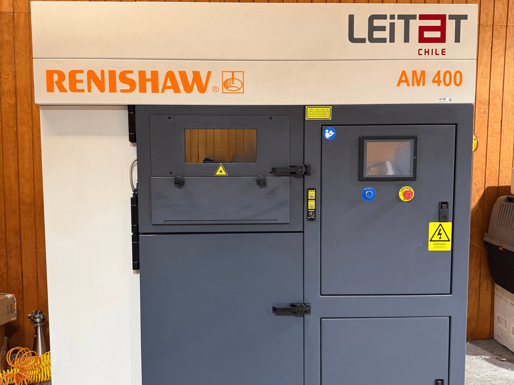 Front view of RENISHAW AM400 metal 3D printer, featuring control panel, warning labels, and maintenance access.
